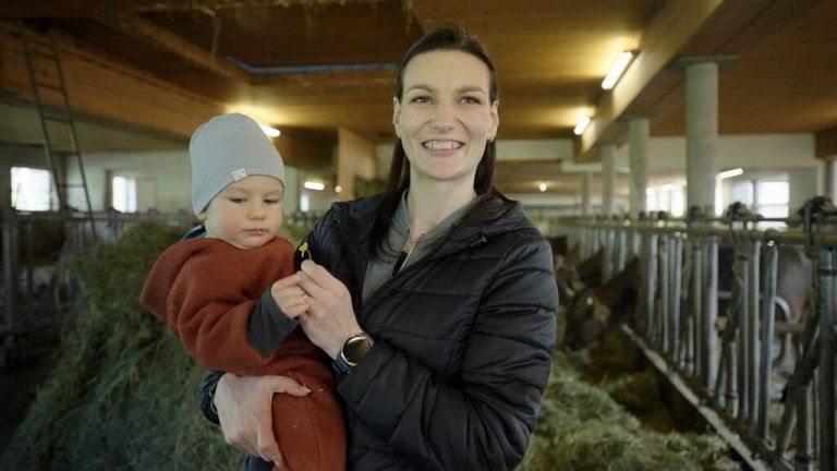 Mutter und Kind fühlen sich inmitten von Heu und Kühen wohl.