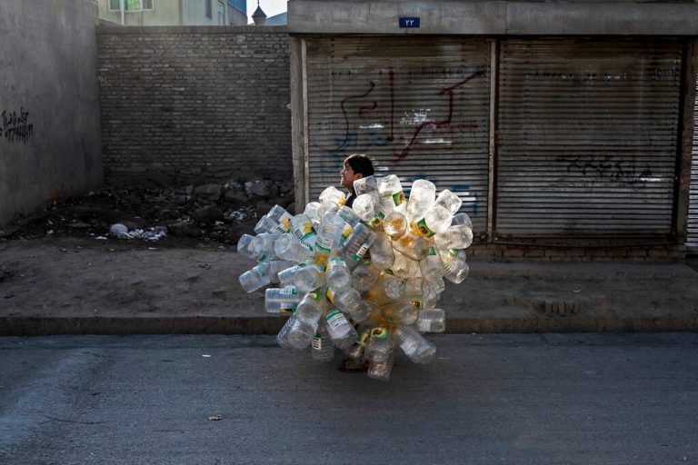 Ein afghanischer Junge geht mit leeren Plastikdosen eine Straße in Kabul entlang. AFP