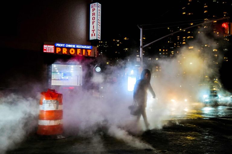 Eine Frau überquert bei Minus­temperaturen eine Straße im New Yorker Stadtteil Manhattan, während Dampf aus dem Boden entweicht. AFP