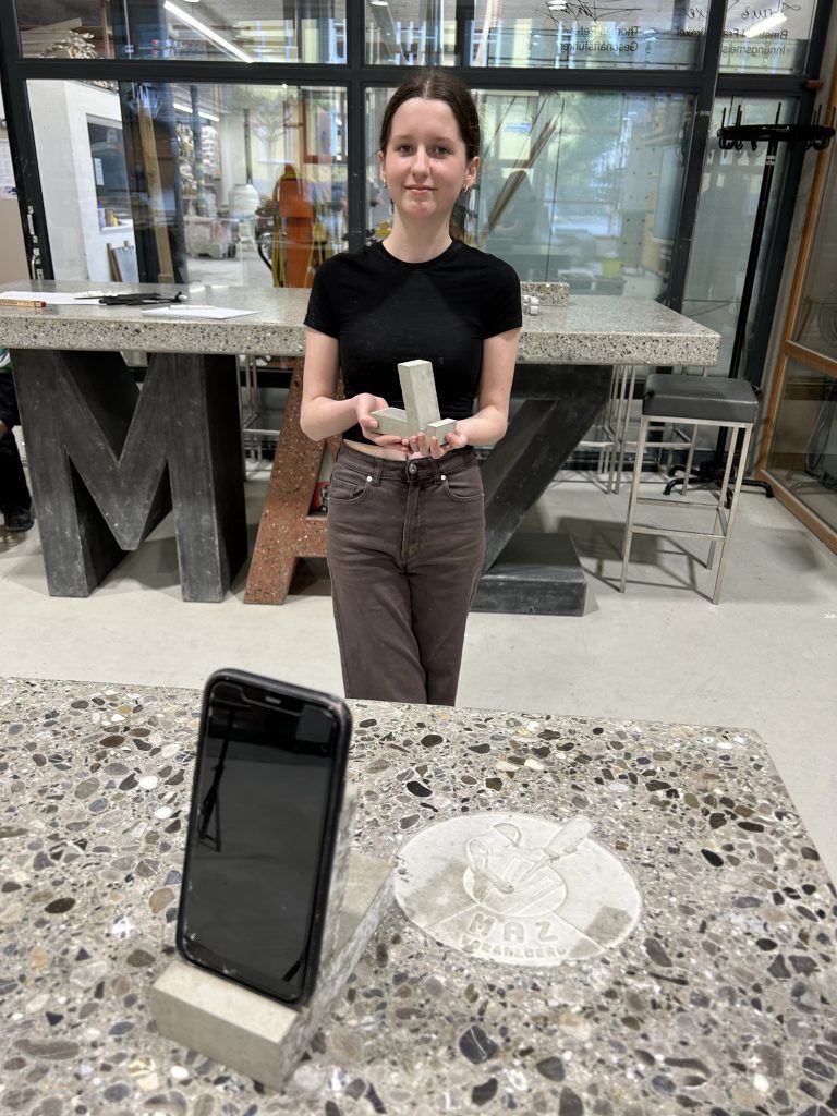 Lisa Heim mit ihrem selbst betonierten Handyhalter. - PTS Dornbirn Baubrancheschnuppern