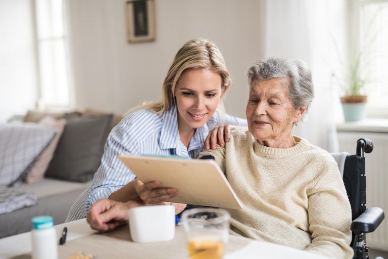 A health visitor measuring a blood pressure of a senior woman at home.