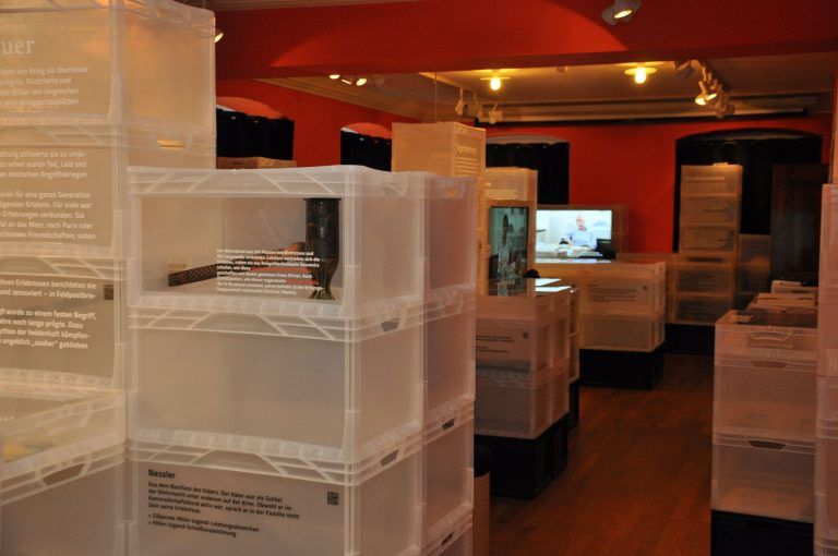 Kisten voller Erinnerungen an eine düstere Zeit: Die Artefakte aus der Zeit des Nationalsozialismus sind in milchigen Kunststoffboxen ausgestellt.