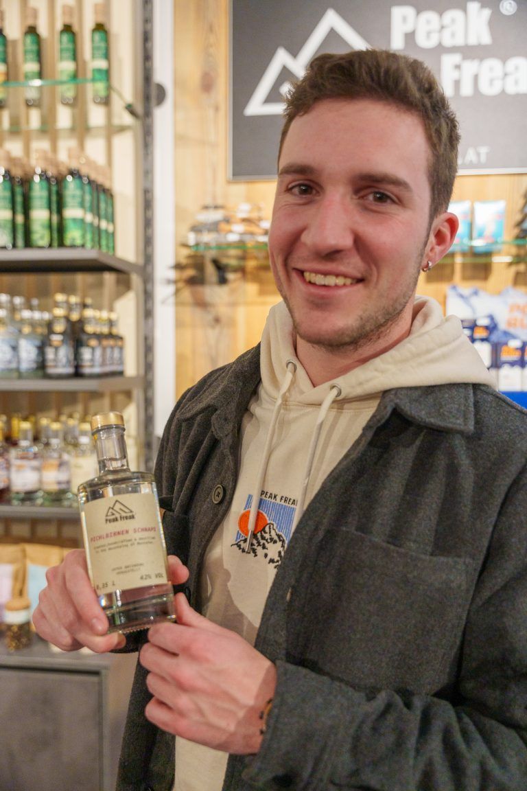 Peak Freak eröffnet zweiten Store in Brand mit regionalen Spezialitäten und personalisierten Produkten: Patrick Ladner mit dem eigens von Patrick Säly zur Eröffnung kreierten Peak Freak Pichlbirnenschnaps.