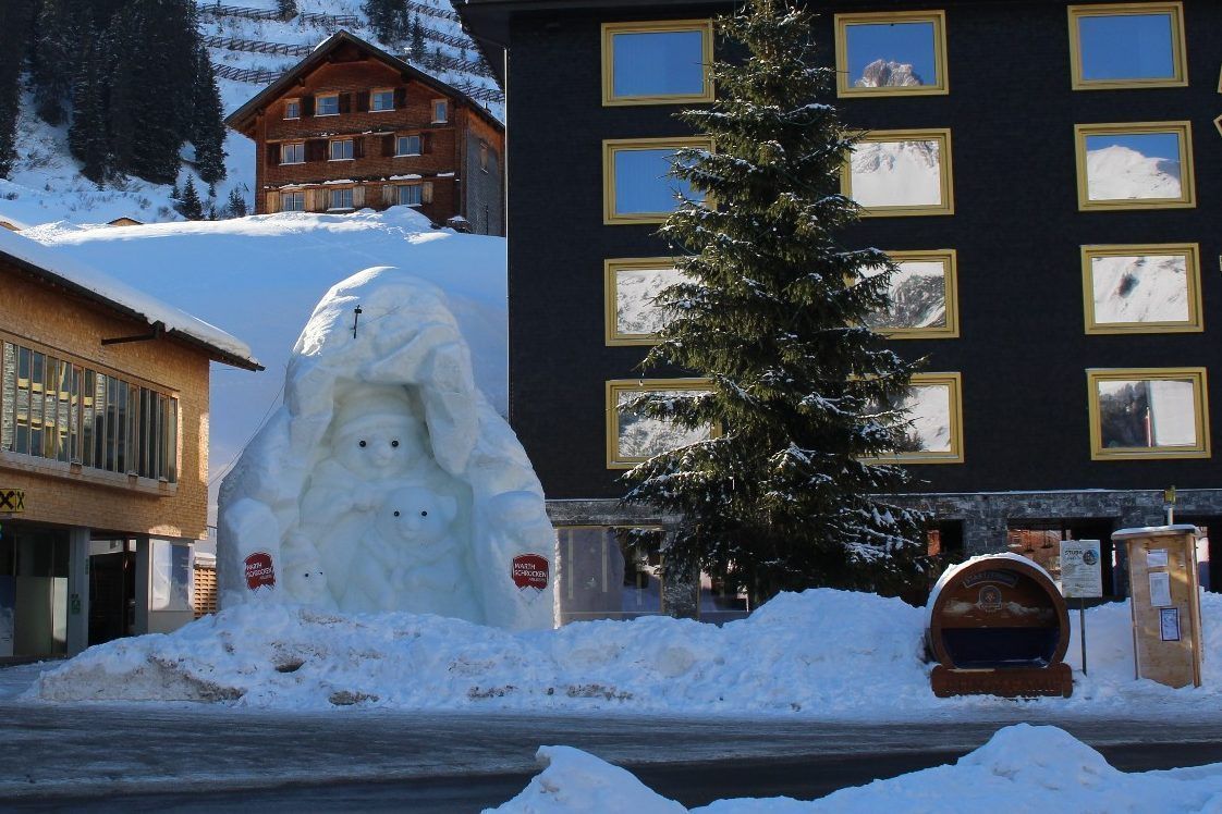 Bärig – Warth hat ein neues Eiskunstwerk: Unübersehbar thront die eisige Bärenfamilie als Blickfang zwischen Mehrzweckzentrum und Hotel Biberkopf, in dessen Fenstern sich der echte Biberkopf spiegelt.