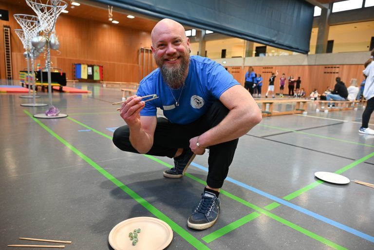 Magische Olympiade an MS Mittelweiherburg: Bei Freizeitpädagoge Andy wurde die Geschicklichkeit der Schüler auf die Probe gestellt: Sie durften Glasmurmel mit Holzstäbchen transportieren.