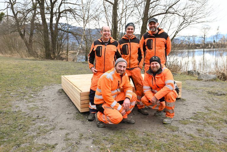 Die Bauhof-Mitarbeitenden Reini Fitz, Christian Werth, Marc Zigarnek, Hervog Barsechian und Günther Harrant zeigen Stolz ihre neu gemachte Holzliege am Alten Rhein.