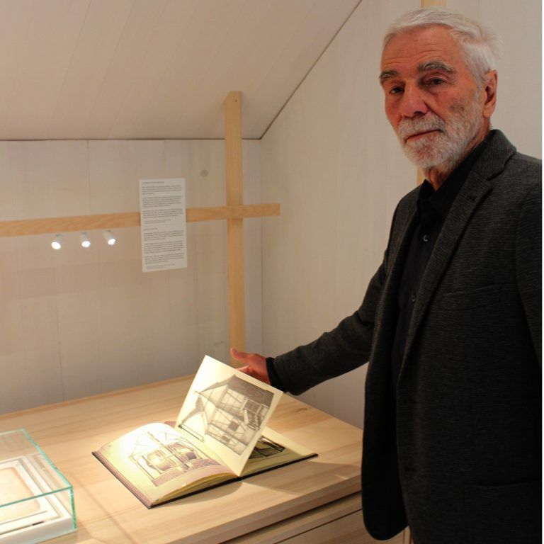 Von wegen Museen sind verstaubt . . .: Anton Bär, jahrzehntelanger Leiter des Museums, erläutert ein wertvolles und interessantes „Lehrbuch“ aus dem Fundus des jubilierenden Bezauer Handwerkervereins.
