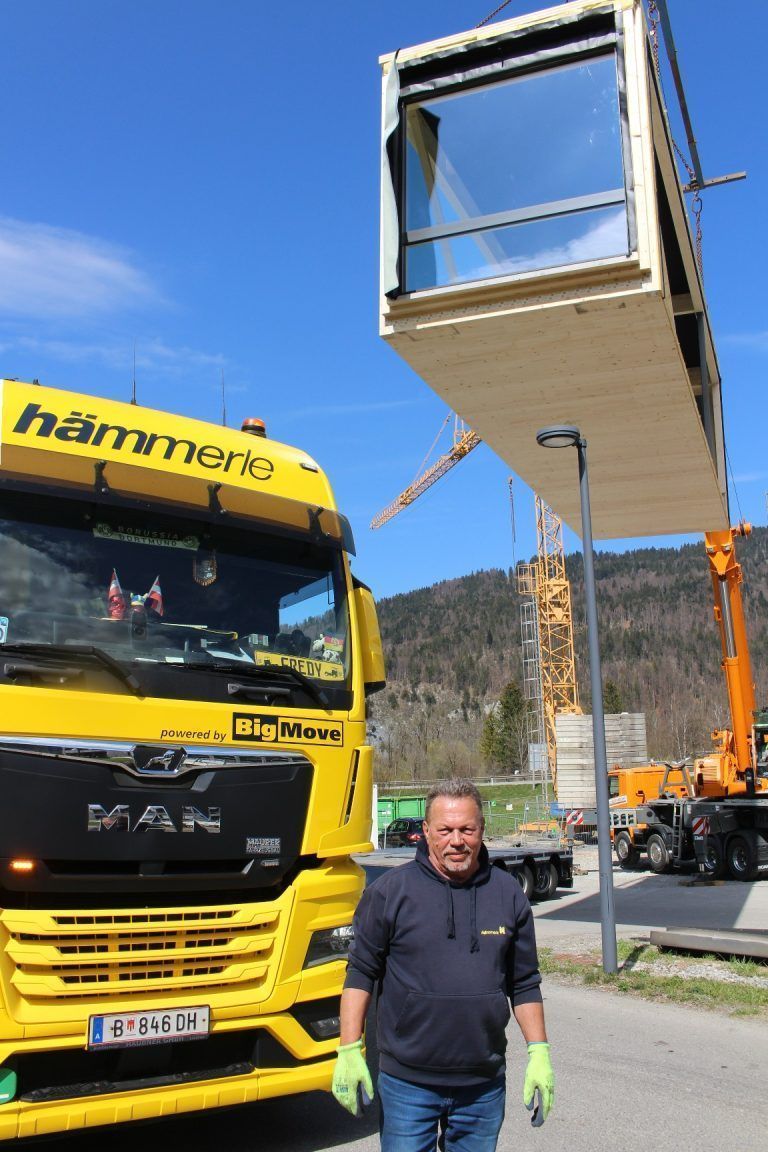 Kaufmann Bausysteme erweitert in Reuthe: „Mal was ganz anderes“, meinte Fredy Hillberger, denn die Fahrt von der Produktionshalle zur Baustelle war keine 300 Meter lang und führte nur „um zwei Hausecken“. Normalerweise transportiert er Module von Kalwang über rund 750 km nach Berlin oder mehr als 1.000 km nach Rostock oder Hamburg.