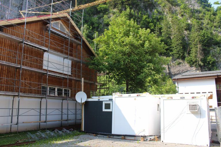 Zubau und Update für Auer Vereinehaus: Im Zuge der Baumaßnahmen wird das aus den frühen 1990er-Jahren stammende Gebäude auch thermisch saniert. Rechts im Bild die Ausweichcontainer.