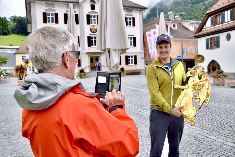 Jahrhundertealter Münsterengel wird restauriert: Werner Ganahl fotografiert seinen Neffen Dominik mit dem Schrunser Münsterengel am Kirchplatz.