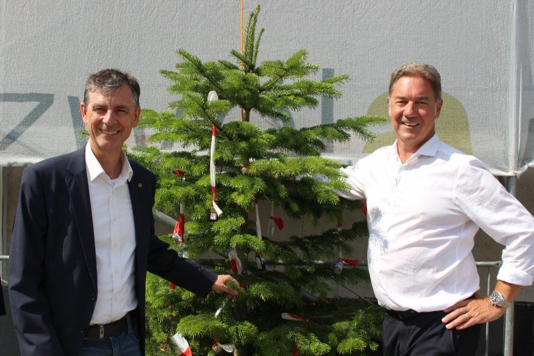Vom Raiba-Projekt grüßt der Firstbaum : Raiffeisen-Vorstandsvorsitzenden Michael Alge (l.) und zwei-a-Geschäftsführer Alexander Stuchly strahlten mit der Sonne um die Wette, als sie das Kommando zum Aufziehen des Firstbaums gaben.