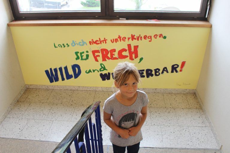 Unsere Schule ist schöner geworden: Elena Hinteregger vor dem Motto der kleinen Malermeister . . .