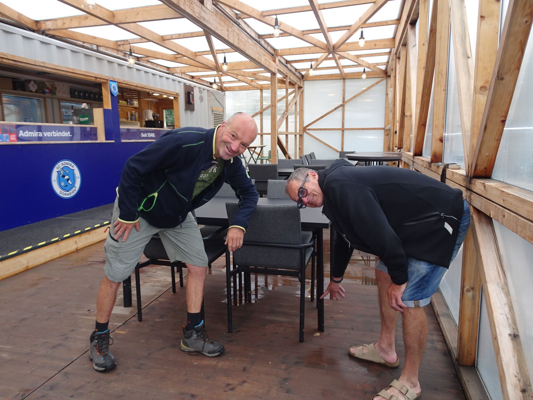 Markus Roy und Reini Peer zeigen auf den durchnässten Boden im provisorischen Clubheim. 