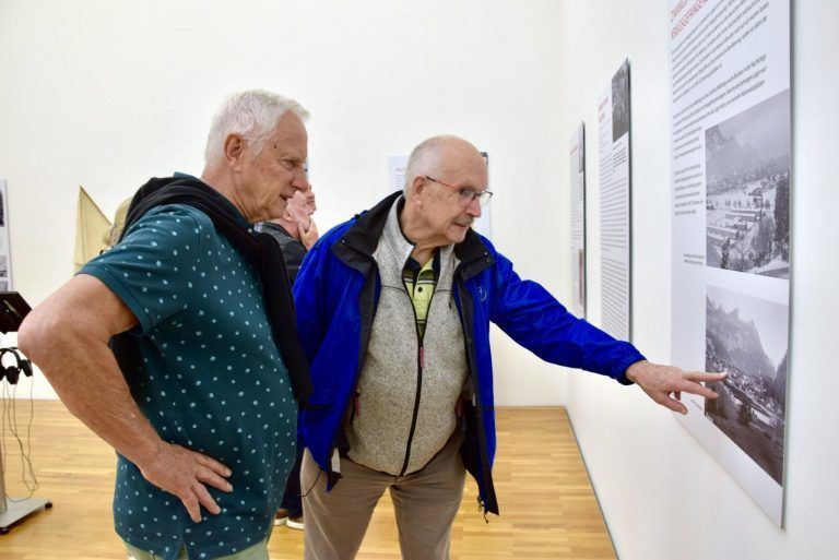 "Die Menschen litten wirkliche Not": Der ehemalige Vorarlberger Landtagsabgeordnete und Bürser Bürgermeister Helmut Zimmermann (vorne) sowie Otmar Branner informieren sich in der Bludenzer Sommerausstellung 2025.