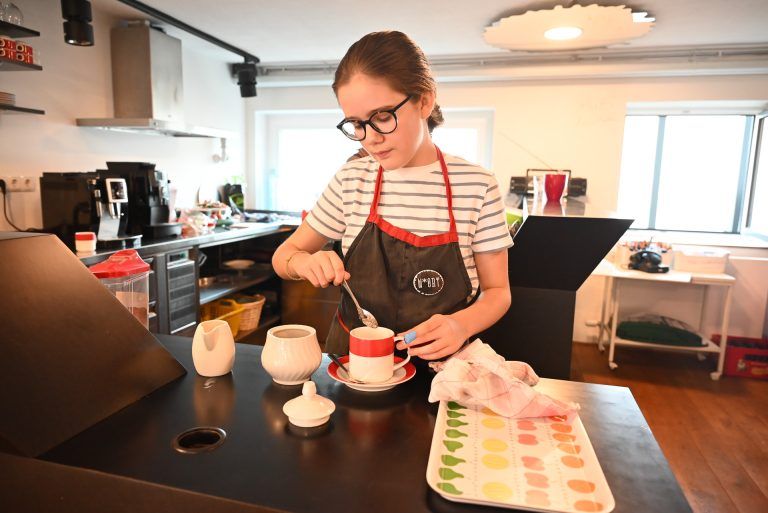 Mit Schürze, Charme und einer großen Portion Freude: Zucker und Milch kommen noch in den Kaffee.