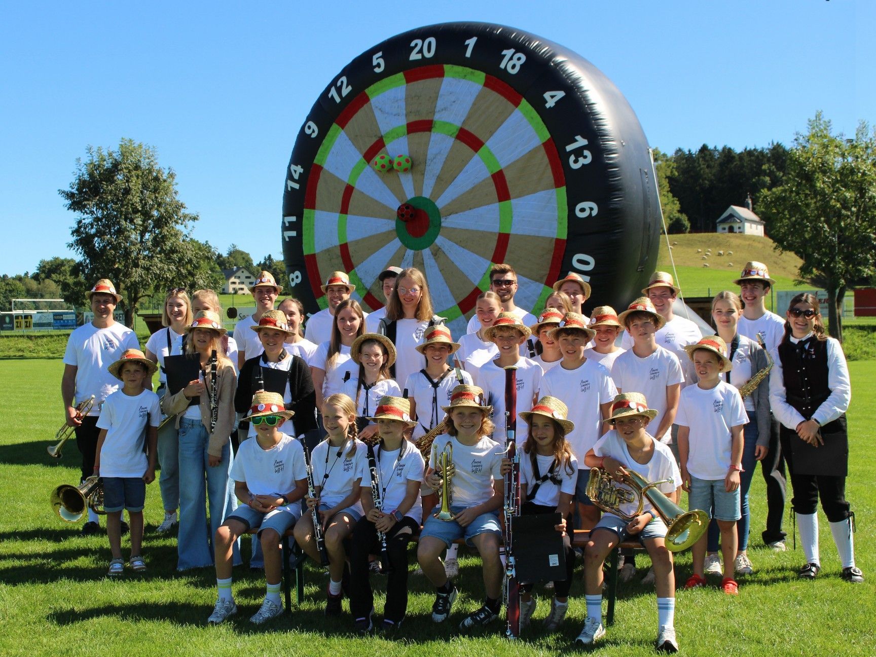 Gruppenbild der Jugendmusik „Zemma sind mir MEH“ vor der riesigen Fußball-Dart-Scheibe.