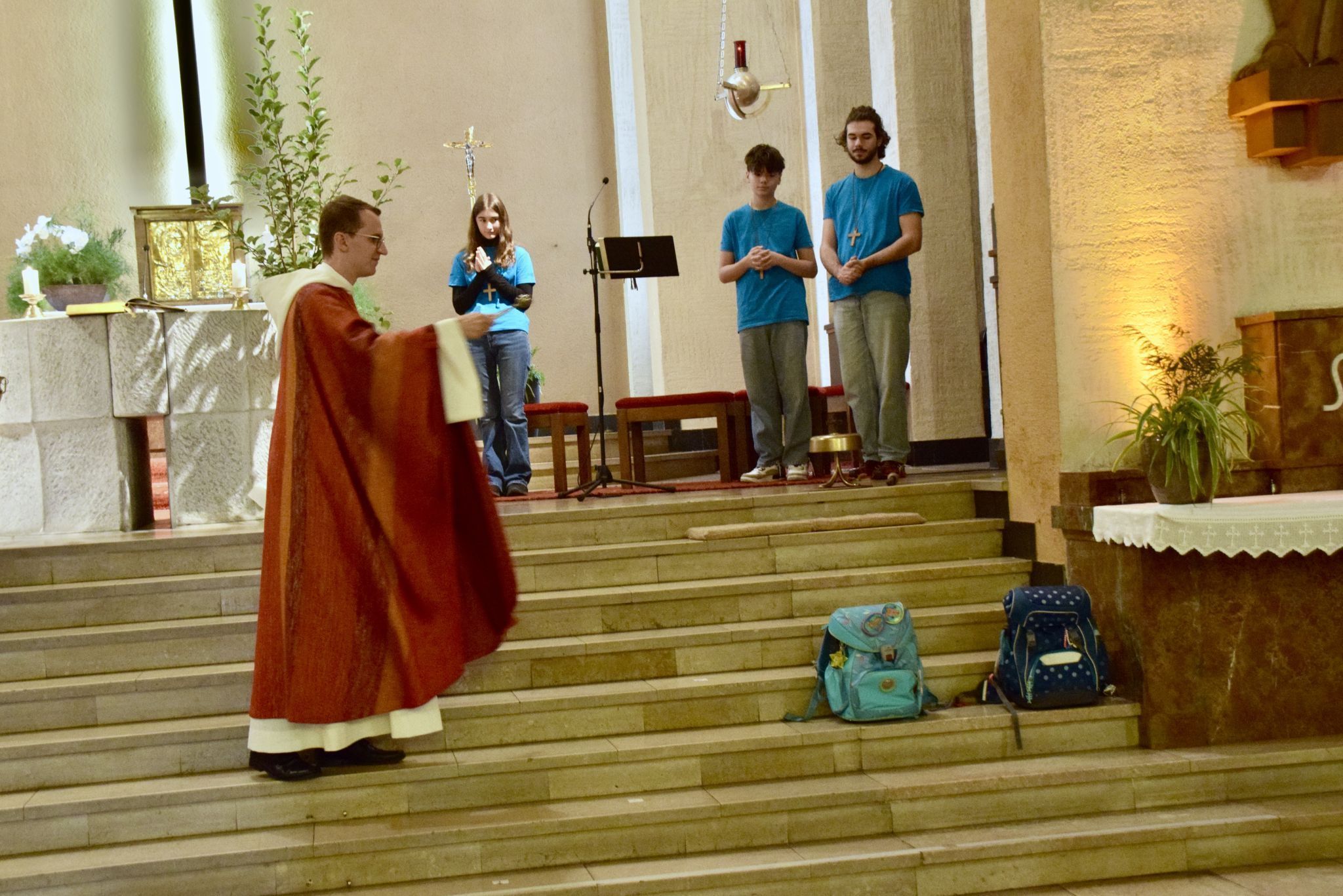Kaplan Jakob Geier bei der Schultaschensegnung (weitere Taschen befanden sich in den Kirchenbänken).