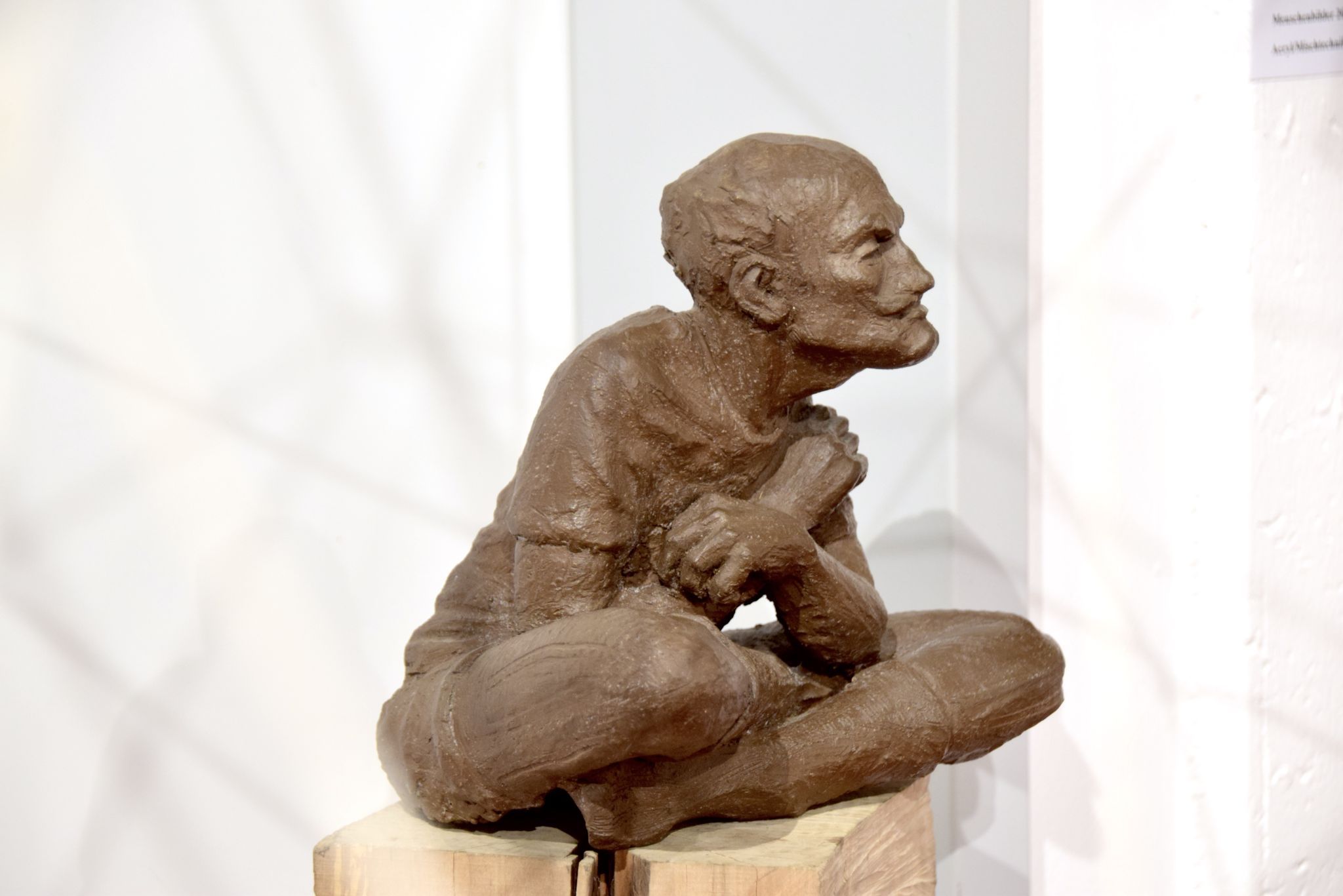 Daniel Bragagna, 2024: „The Seated One“ - zweifach gebrannter Ton, Holzsockel mit Eisenplatte, Unikat.