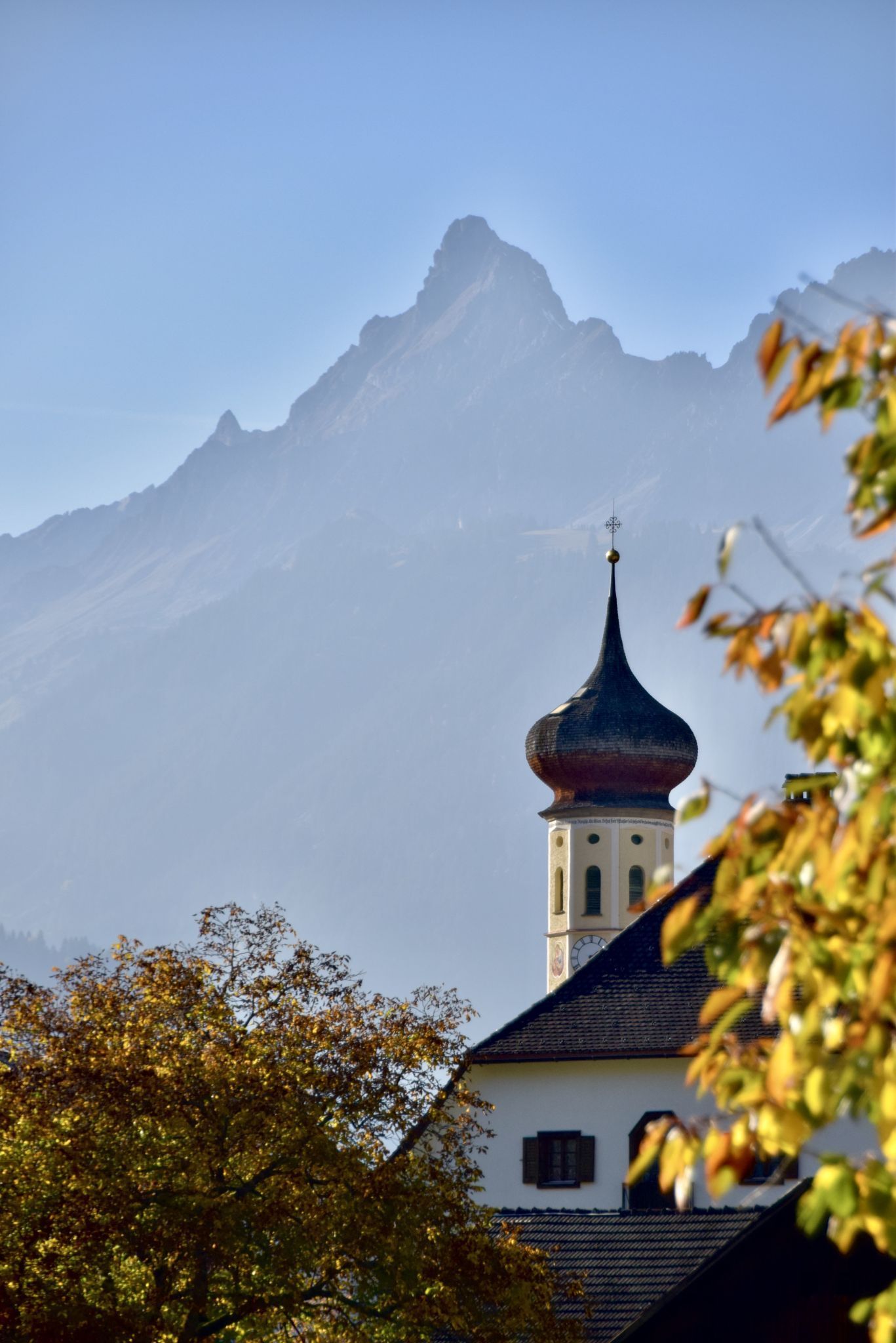 Eine Teilansicht des mehr als 40 Meter hohen Schrunser Münsterturmes mit der 2643 Meter hohen Zimba, der höchsten Erhebung der Vandanser Steinwand, im Hintergrund.