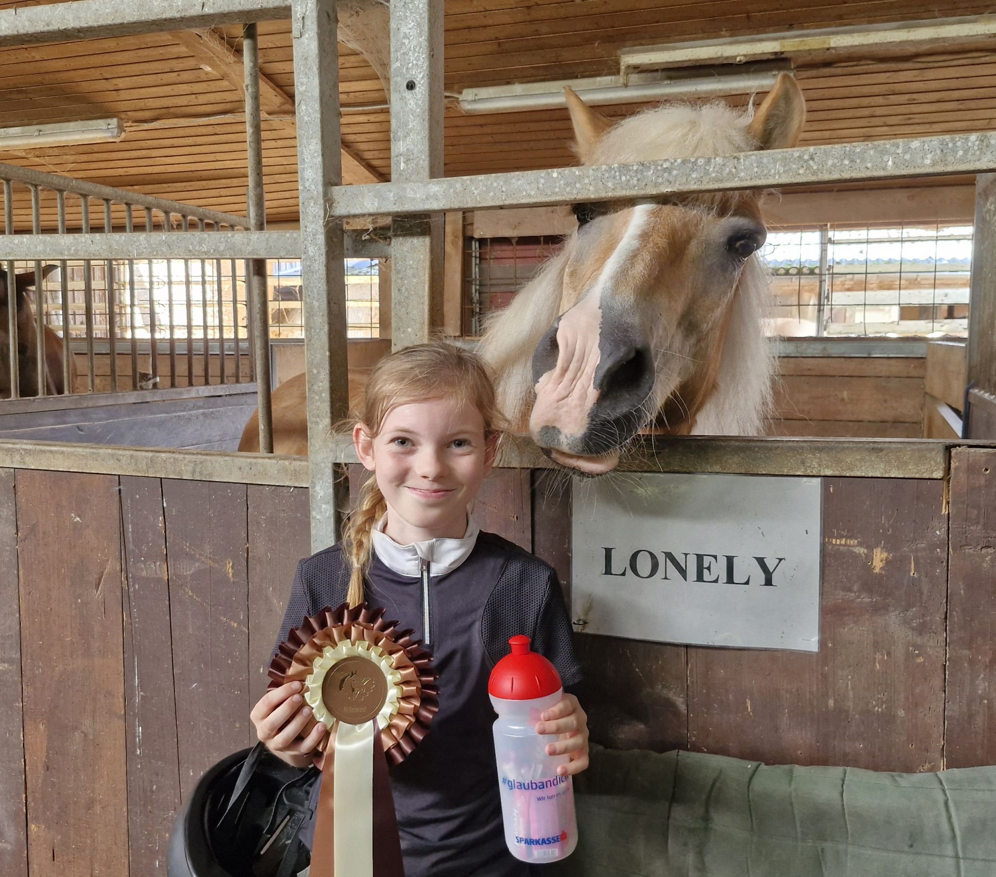 (Bild Wohlgenannt) Stolz zeigt die Zwölfjährige ihre Plakette, für ihren ersten Sieg bei einem Reitturnier.