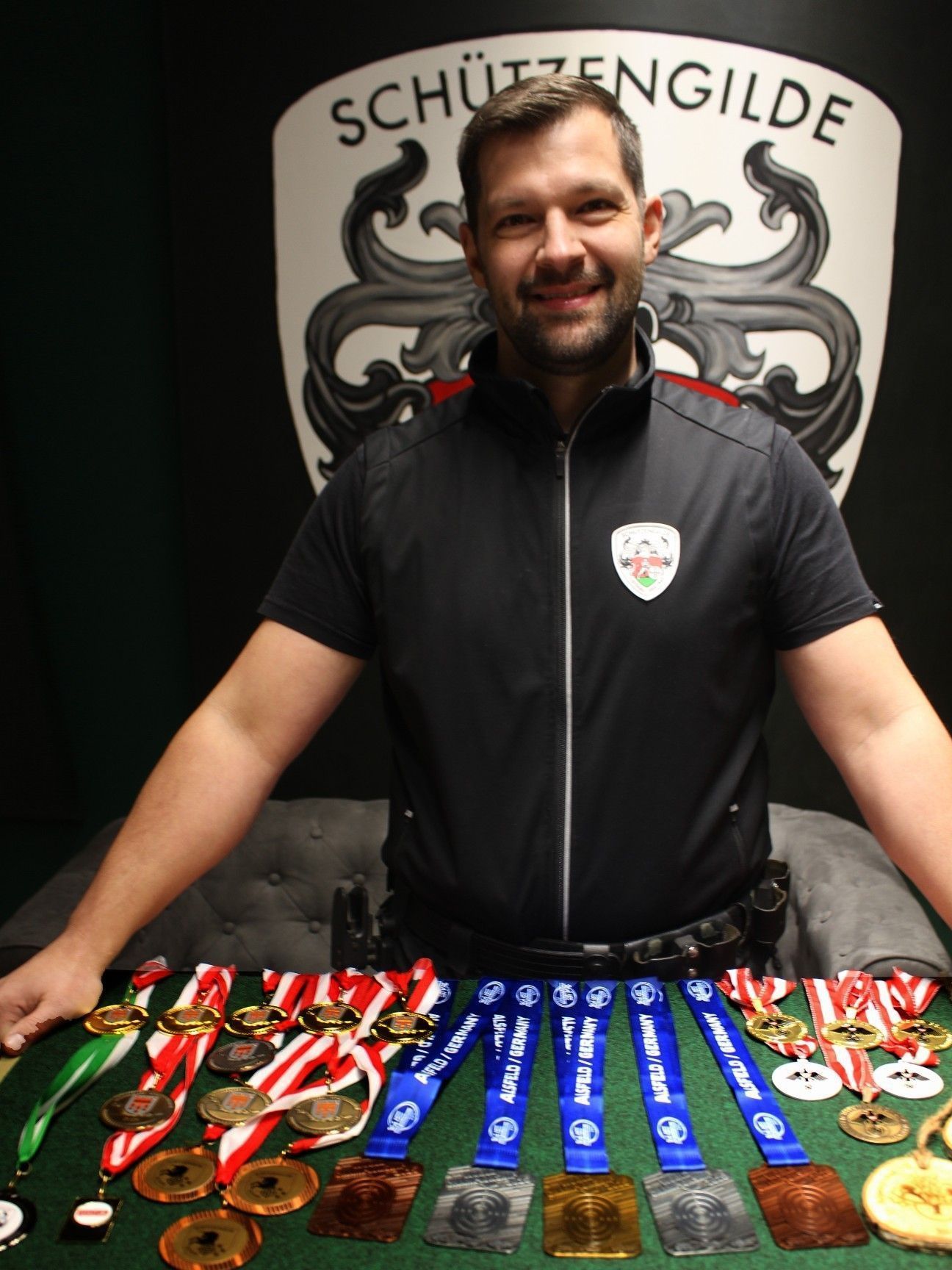 Im „Kino“ des Schützenhauses in Lustenau präsentiert Mario Bentele stolz die Medaillenausbeute des Jahres 2025. Mitten drin Gold und jeweils zweimal Silber und Bronze bei der WM in Alsfeld. PETER STRAUSS