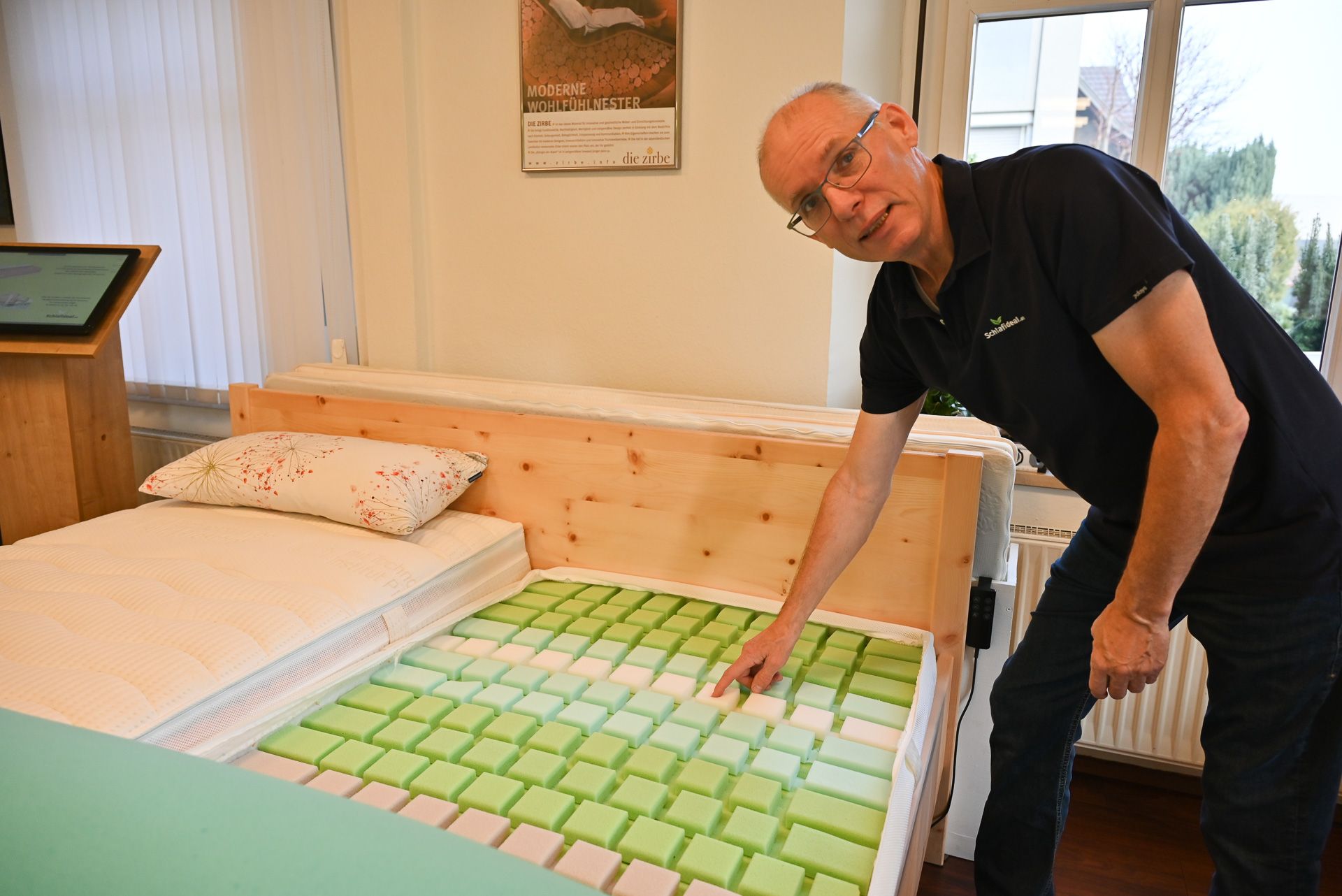 Geschäftsinhaber Mario Aberer demonstriert die 24-Zonen-Matratze, die für die nötige Erholung in der Nacht sorgt.