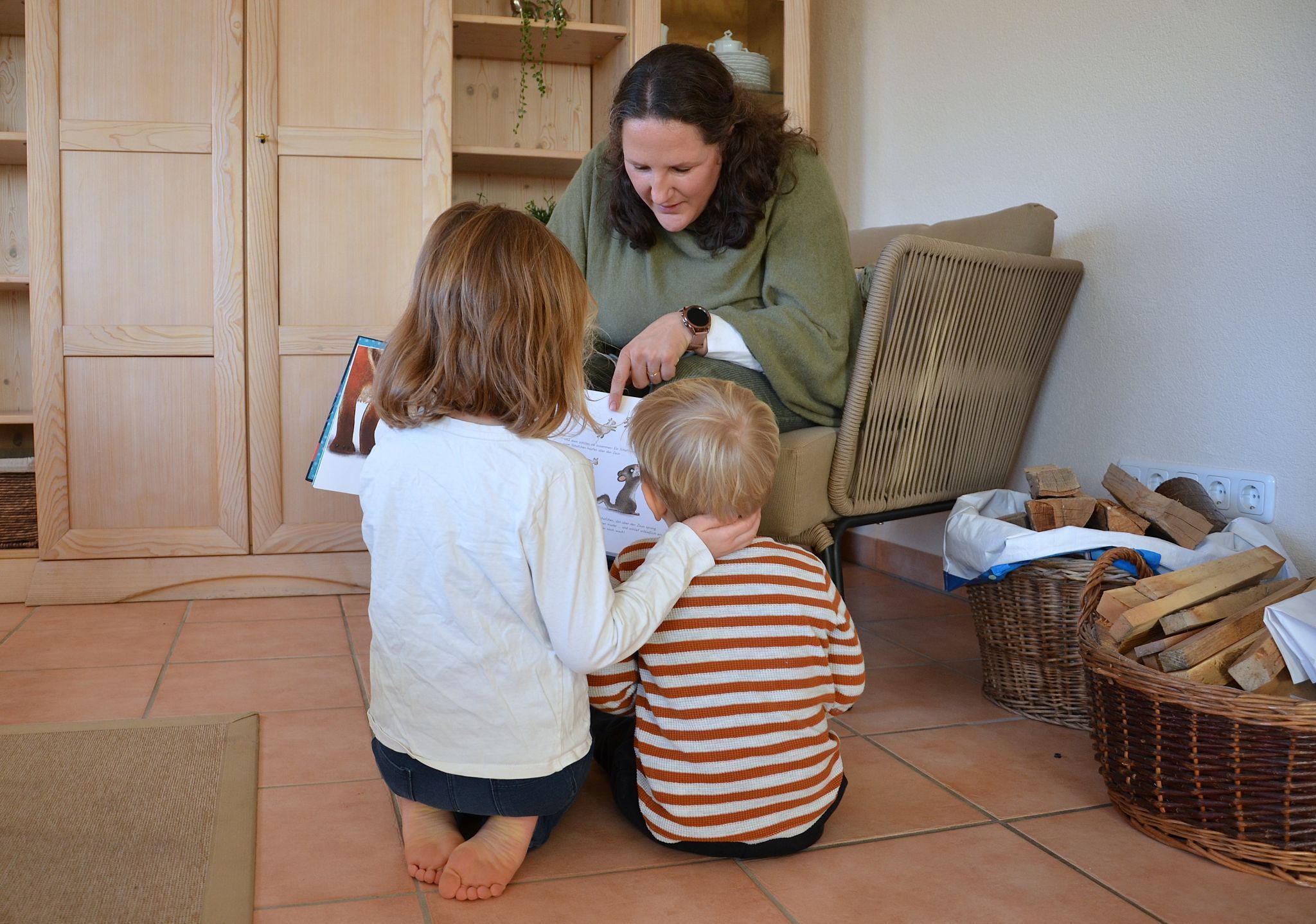 Die sechsjährige Esther und der zweijährige Daniel schauen zusammen mit ihrer Mutter ein Kinderbuch an. HRJ