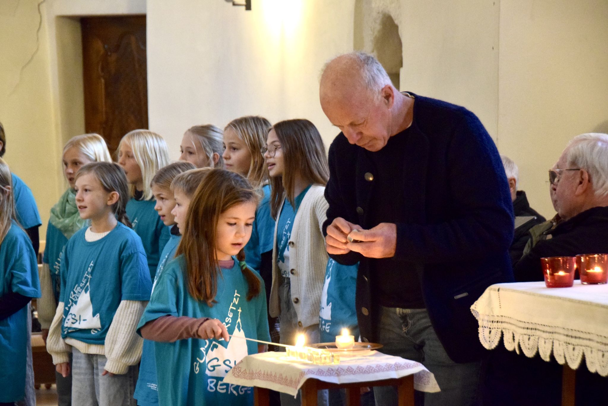 Der Kinderchor St. Anton unter der Leitung von Fabienne Netzer und Michaela Ganahl gestaltete die besinnliche Adventstunde mit. Der Mesner half einem Mädchen beim Entzünden einer Kerze.