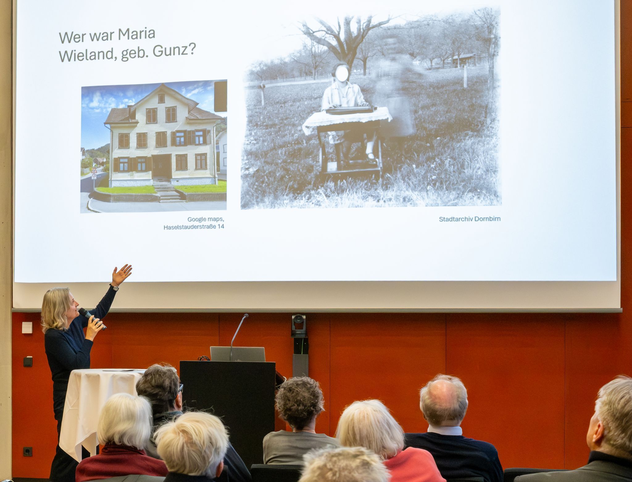 Barbara Motter, Historikerin und Mitarbeiterin des Stadtmuseums, zeigt auf das Bild mit dem Haus Haselstauderstraße 14, der letzten Adresse der Musiklehrerin Maria Wieland. Rechts davon ein Bild einer anonymen Zitherspielerin in Dornbirn.