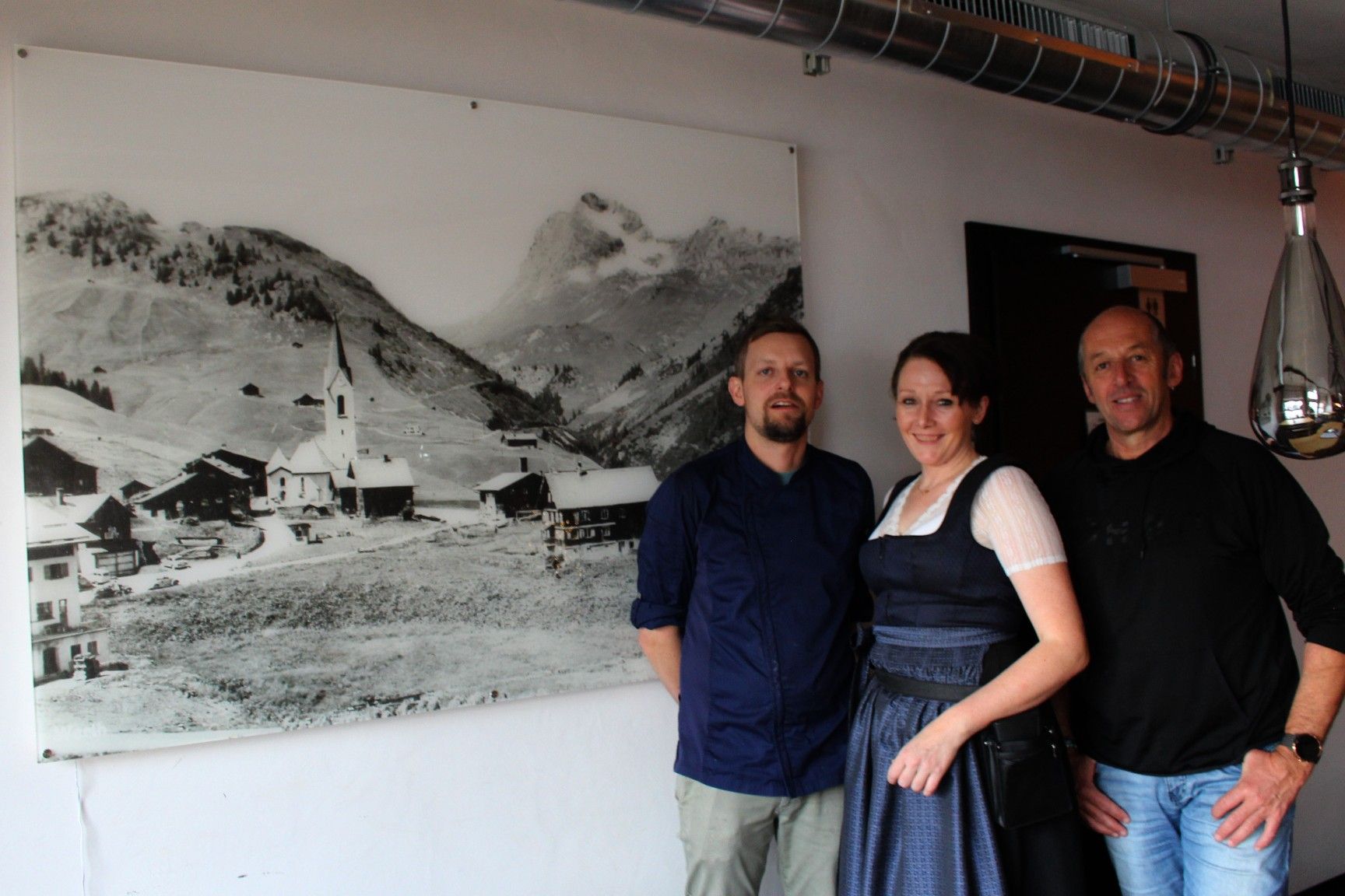 Stolz präsentieren Bürgermeister Stefan Strolz und die neuen Pächter Marina und Michel Niesporek das große Poster, das Auskunft über die Entwicklung von Warth gibt. PETER STRAUSS