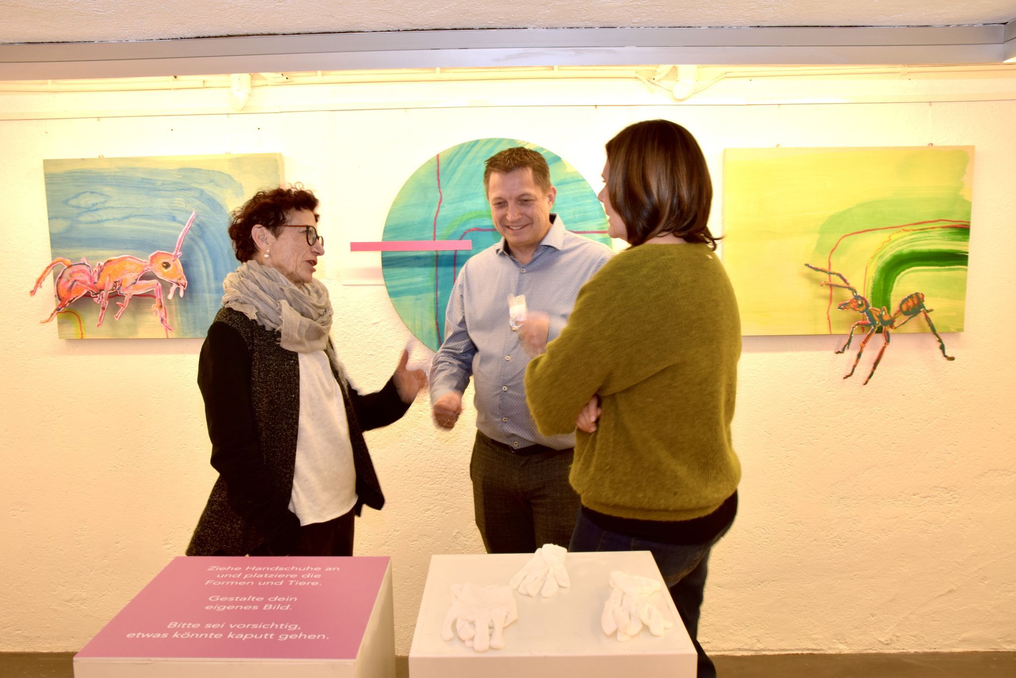 Die Mutter der Künstlerin Rebecca Marent, Roswitha Marent, im Gespräch mit Michael und Ingrid Gantner im Ausstellungsraum mit Werken ihrer Tochter.