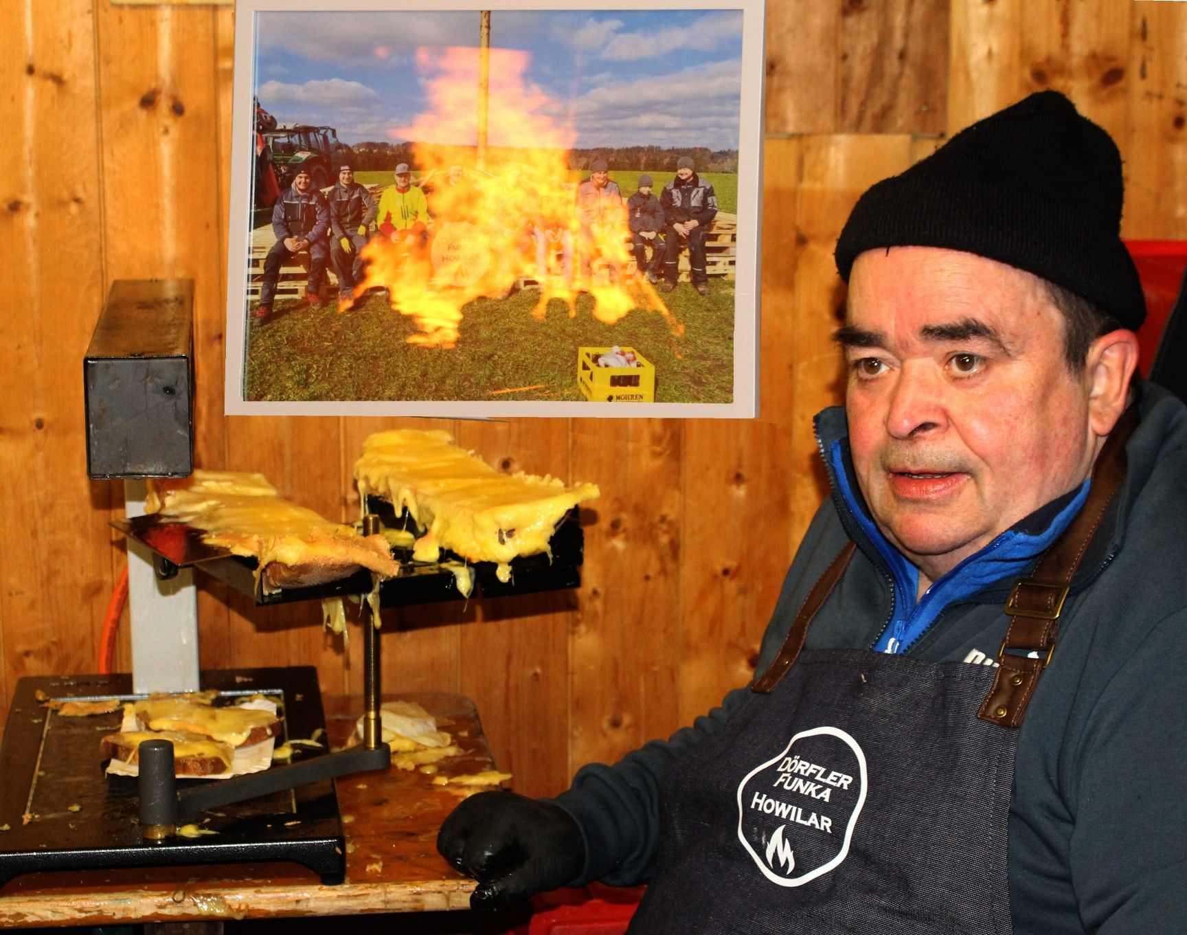 Wise Moosbrugger in einer neuen Rolle – am Raclette-Gerät. Im Hintergrund spiegelt sich der Funken im Glas eines Bildes von einem Funken in einem früheren Jahr.   