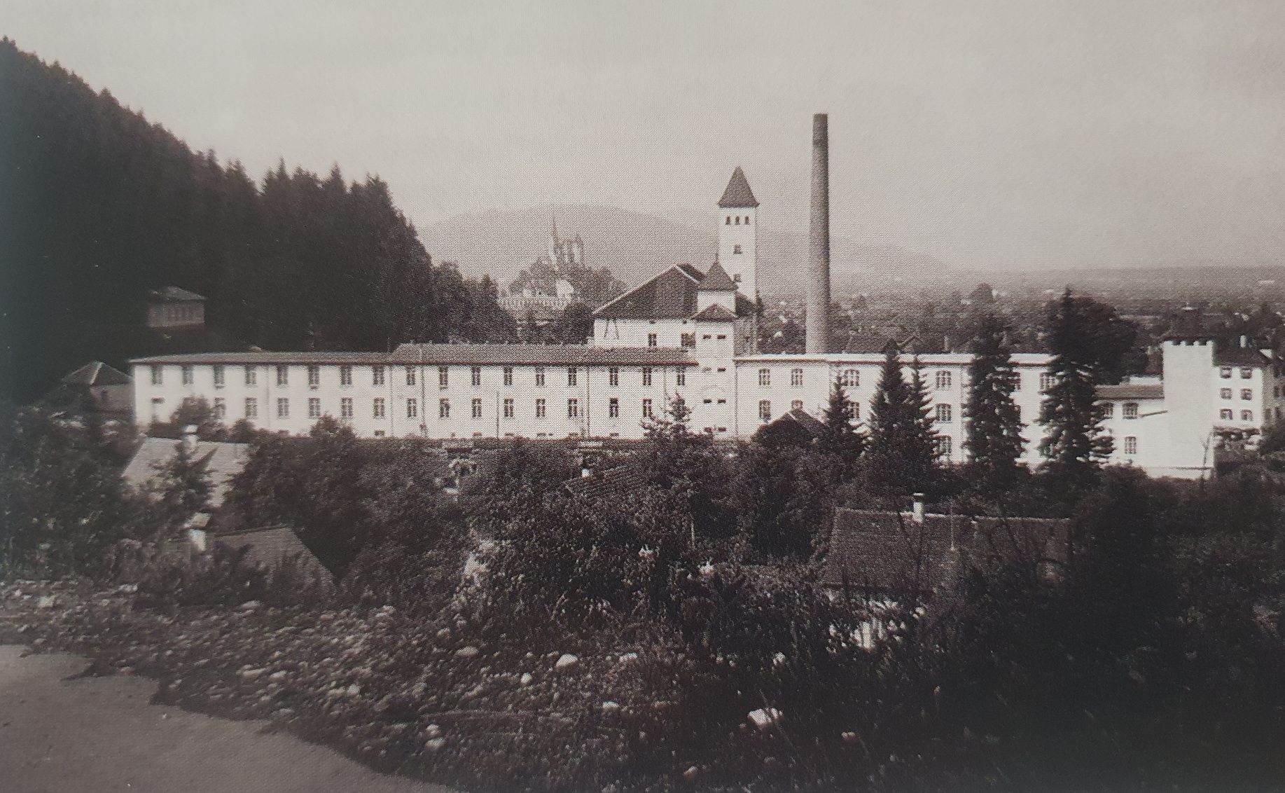 Blick von Zwischenwasser auf die Fabrik im Hintergrund die Basilika Rankweil um 1900. Foto:  Archiv der Marktgemeinde Rankweil.