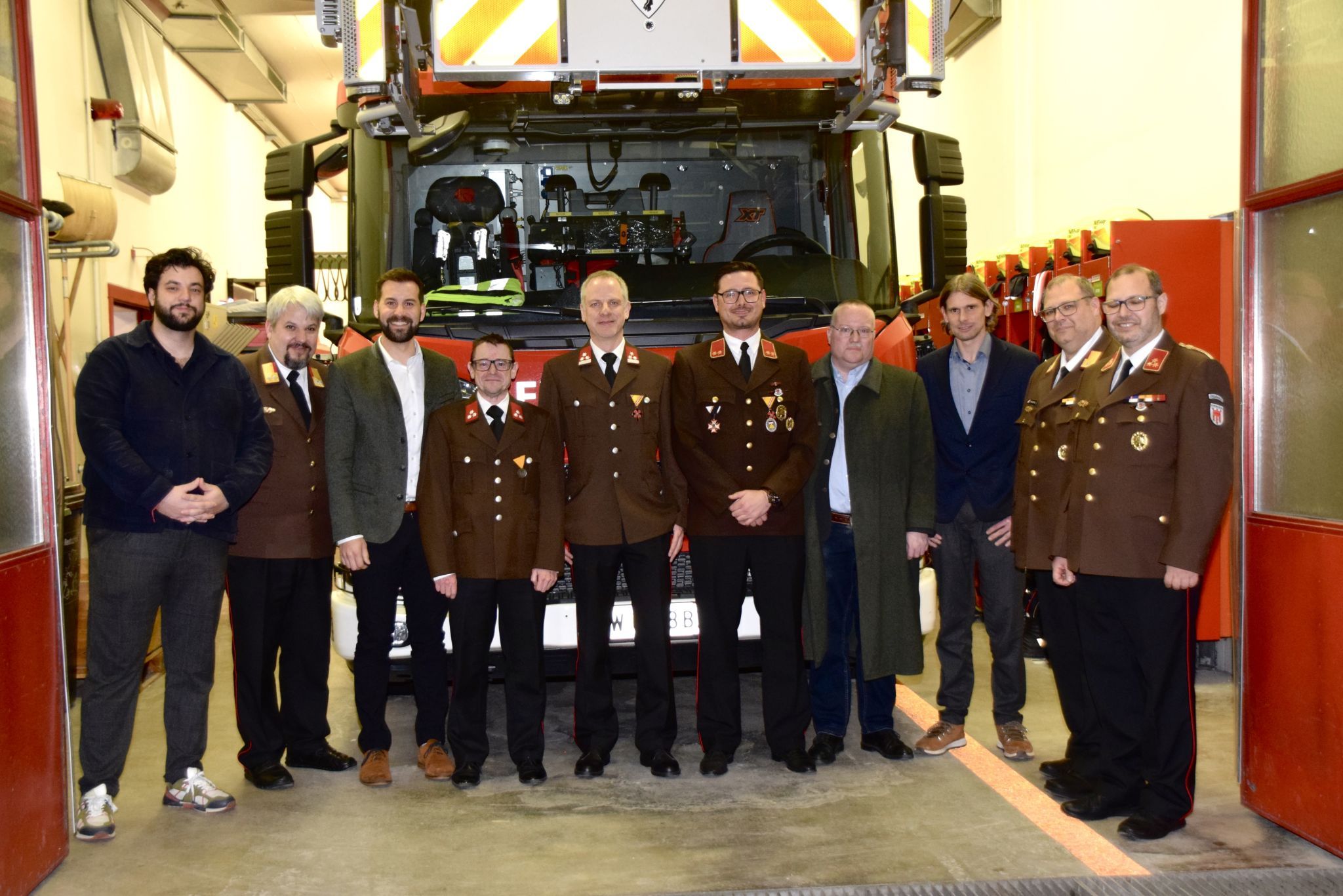 Stadtrat Cenk Dogan, Feuerwehr-Bezirksvertreter Thomas Bargehr, Bgm. Simon Tschann, die drei Geehrten Robert Seeberger, Markus Tomas und Joachim Zoderer, der Bludenzer Bezirkshauptmann Harald Dreher, Stadtrat Bernhard Corn, Abschnittsfeuerwehrkommandant Guntram Vonbun und Feuerwehrkommandant Gunnar Vonbun vor der Drehleiter im Feuerwehrgerätehaus Bludenz.