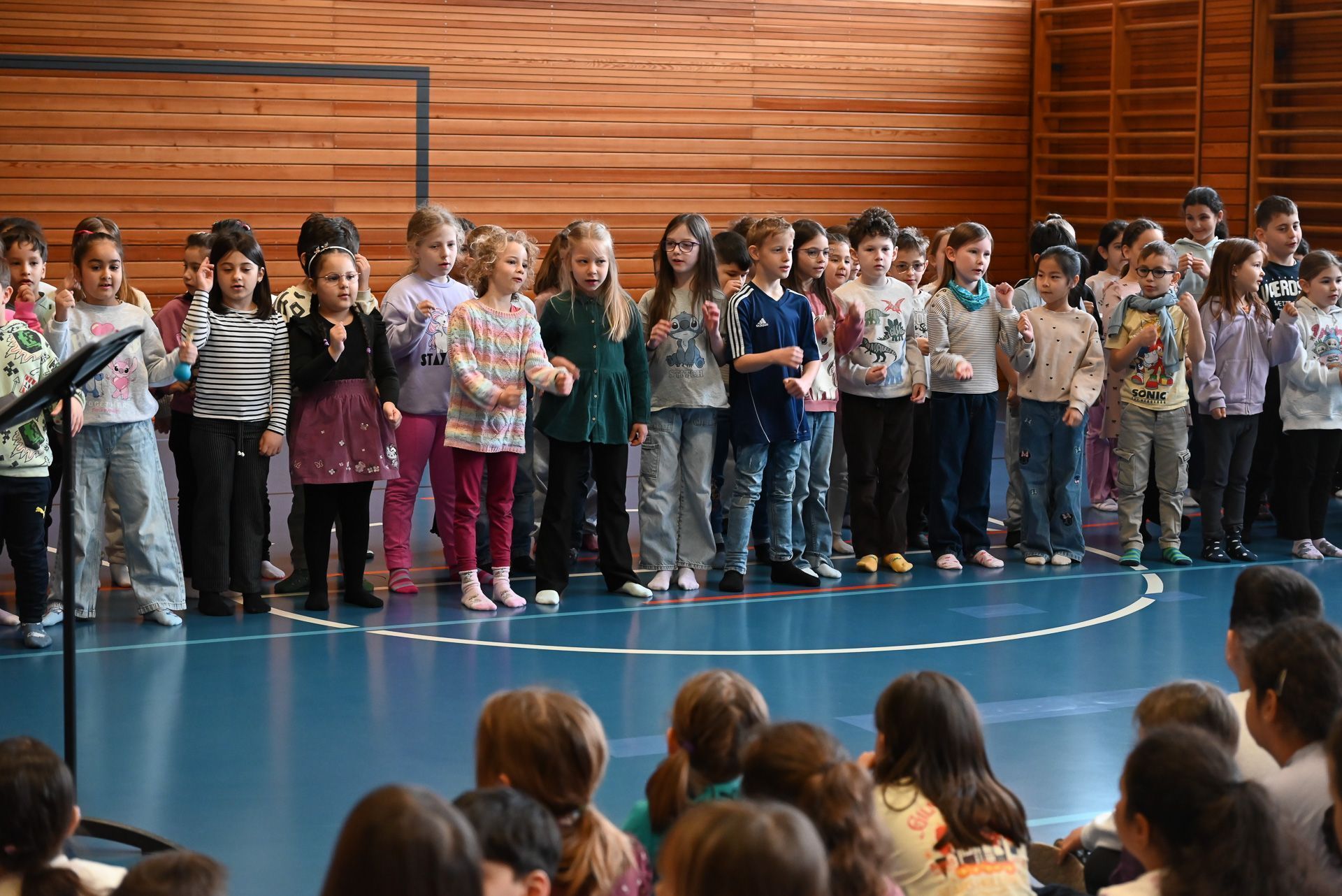 Die Kinder präsentieren stolz ihr gelerntes Lied vor der ganzen Schule.