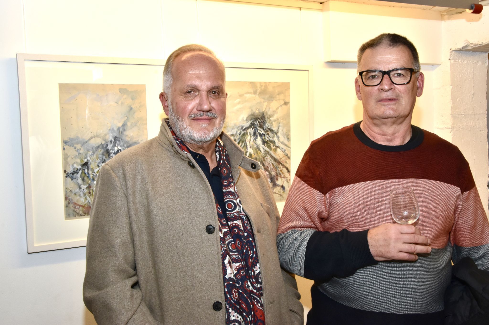 Charly Raser und Kurt Schwaiger in der MAP-Kellergalerie in Schruns, Arbeiten Helmut Schlatters befinden sich im Hintergrund.