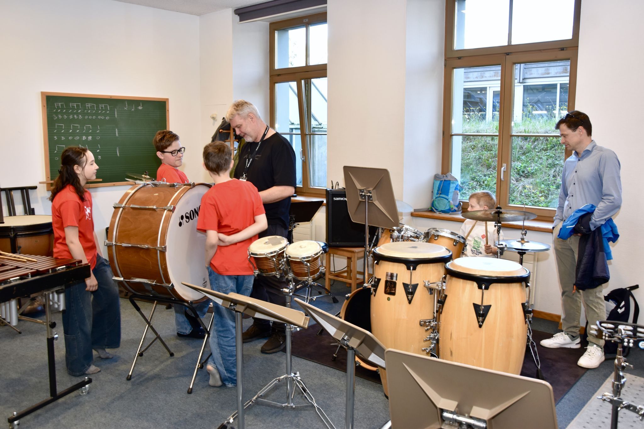 Veronika Huber mit Tochter Amrei am Xylophon. Musikschullehrer Ulli Sparr am Schlagzeug und mit Schülern/Besuchern. Schule im Park in Bludenz. (Bildergalerie)