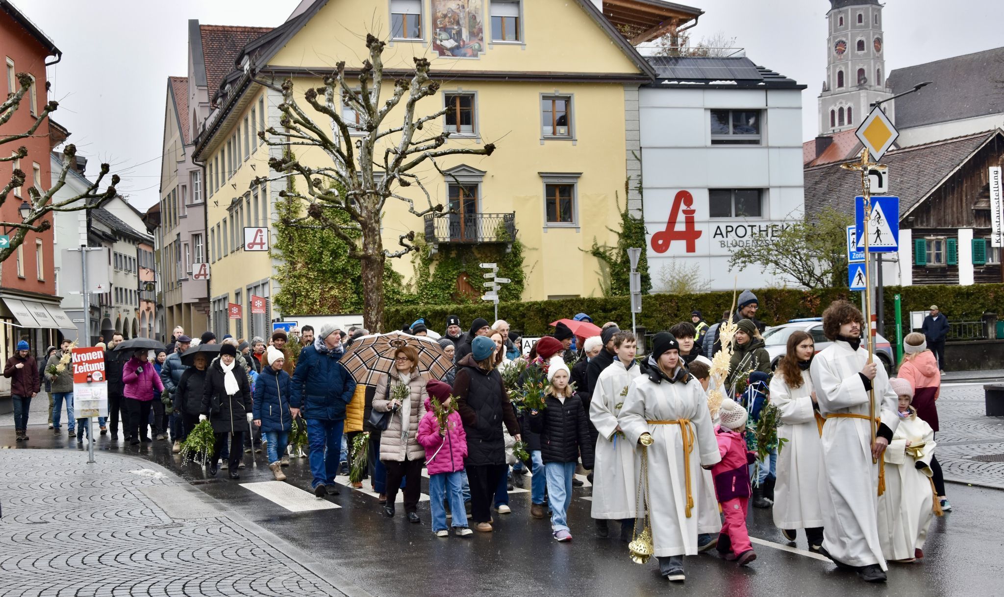 Die Prozession durch Bludenz mit Ziel Pfarrkirche Heilig Kreuz - im Hintergrund eine Teilansicht der St. Laurentiuskirche, Ausgangspunkt der Prozession.