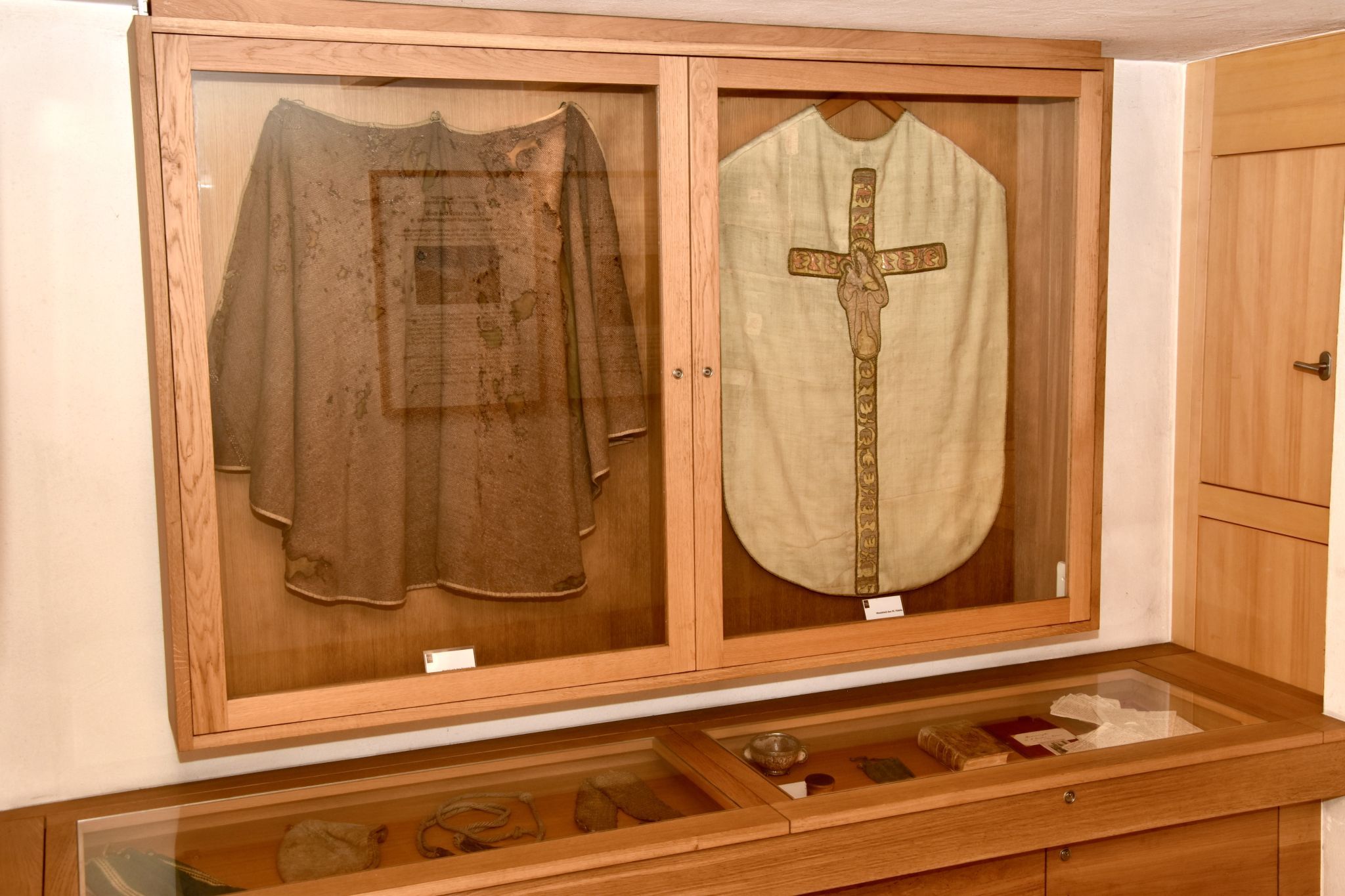Mantel von Fidelis mit den Spuren seines Martyriums (links), daneben das Messkleid des Heiligen in der kleinen Ausstellung im Nebeneraum der Fideliskapelle.