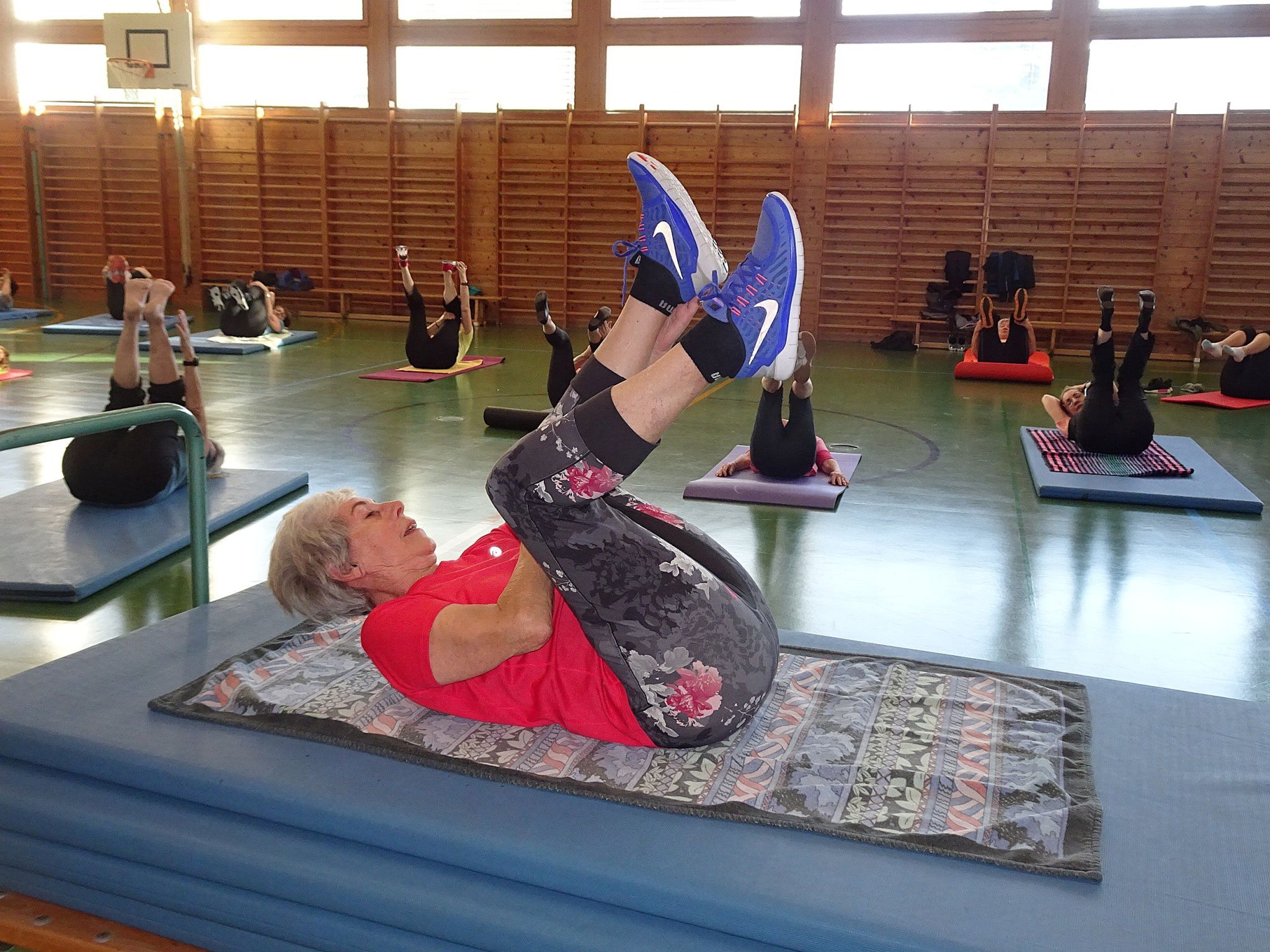 Hedi Mangeng demonstriert die Übung und behält von der Matte aus die Gruppe im Blick.