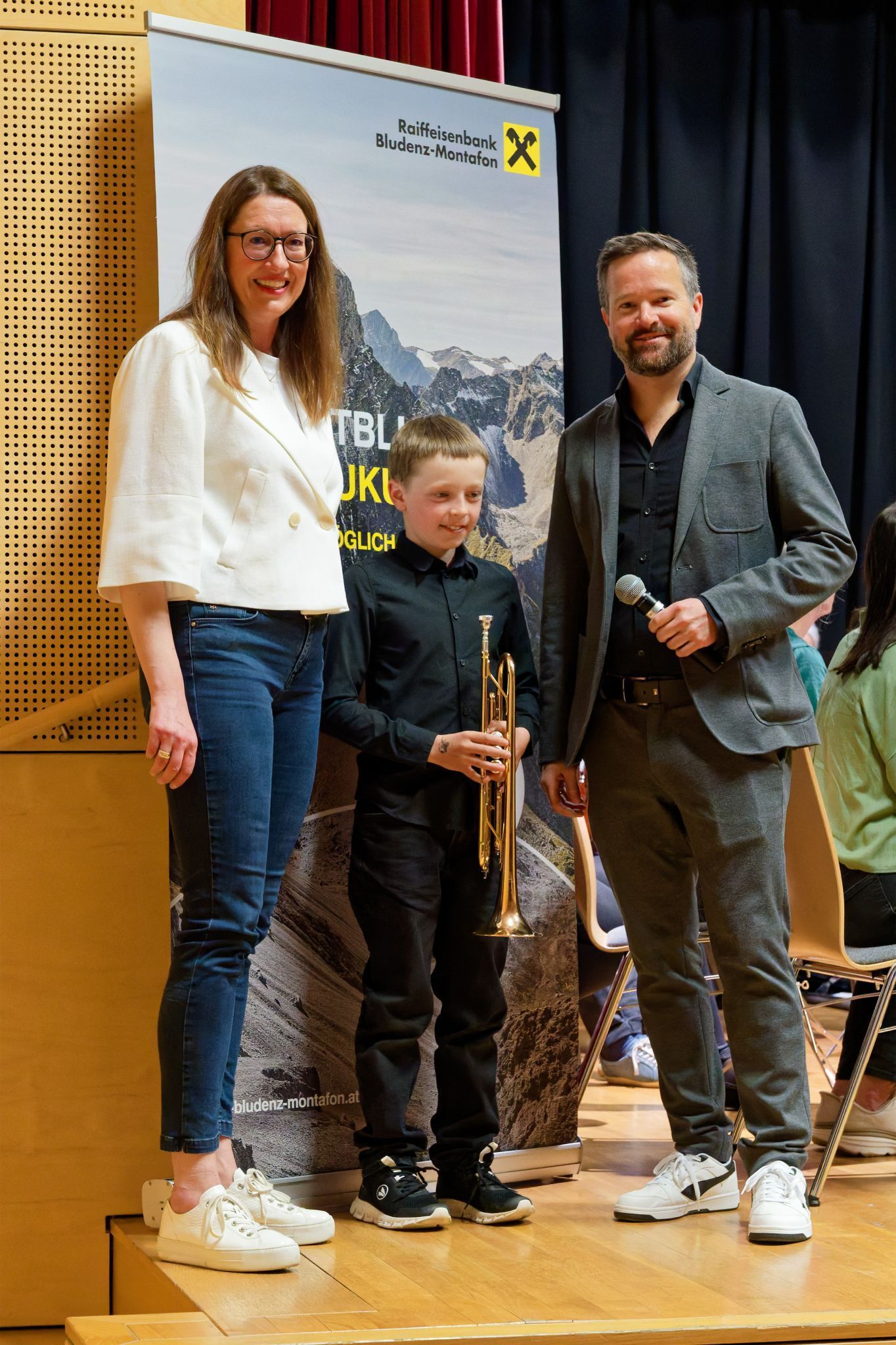 Elisabeth Strassmair (Raiffeisenbank Bludenz-Montafon) und Musikschuldirektor Ralph Hollenstein übergaben symbolisch eine Trompete an den Schüler David Ganahl. Foto: Musikschule Montafon