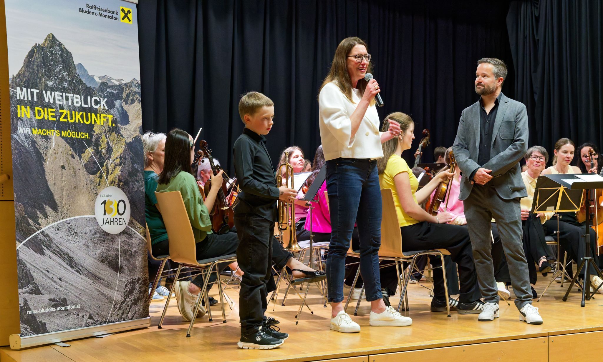 Elisabeth Strassmair (Raiffeisenbank Bludenz-Montafon) und Musikschuldirektor Ralph Hollenstein übergaben symbolisch eine Trompete an den Schüler David Ganahl. Foto: Musikschule Montafon