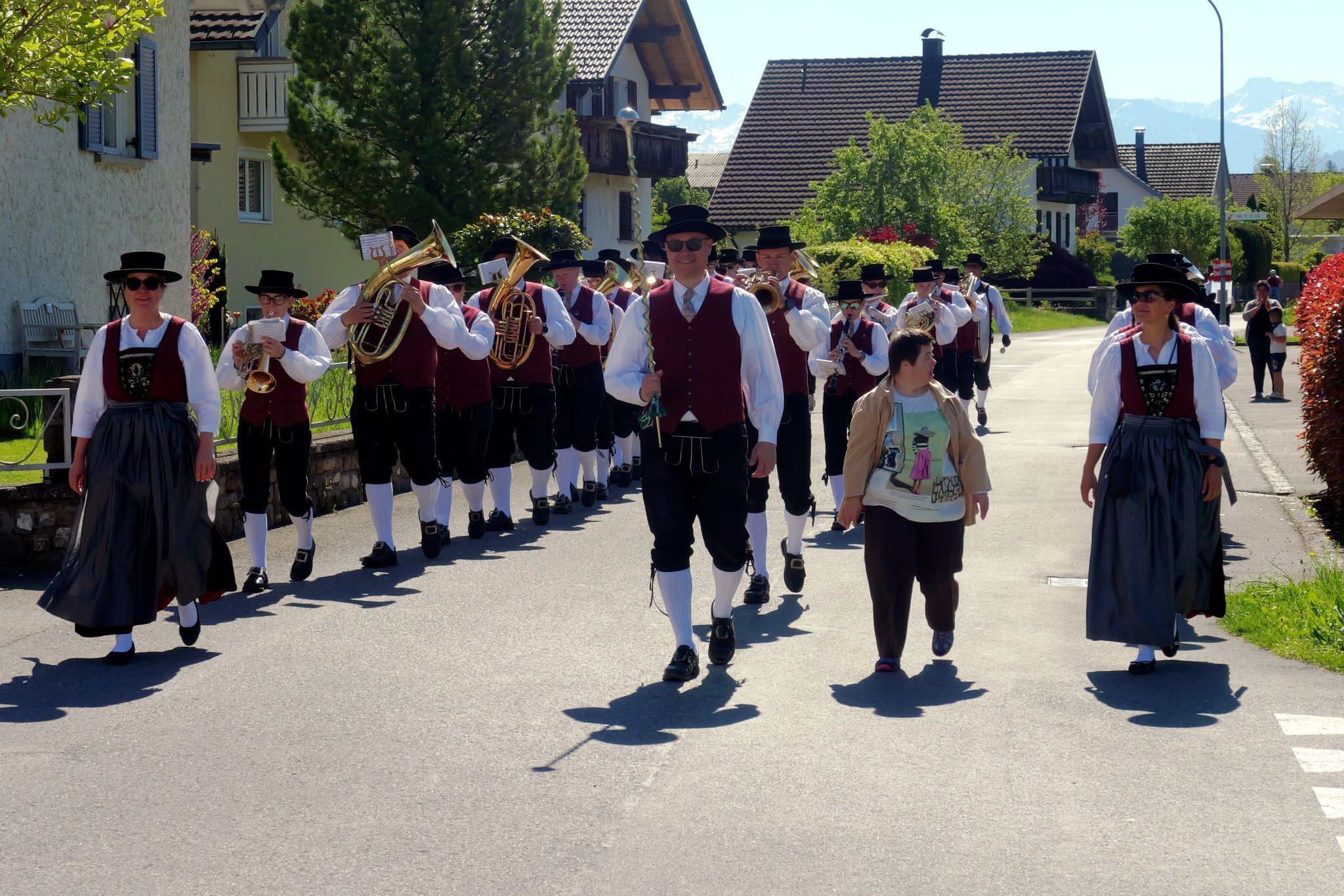 Fröhlich marschiert die Musikkapelle bei schönstem Wetter durch Sonnenheim.