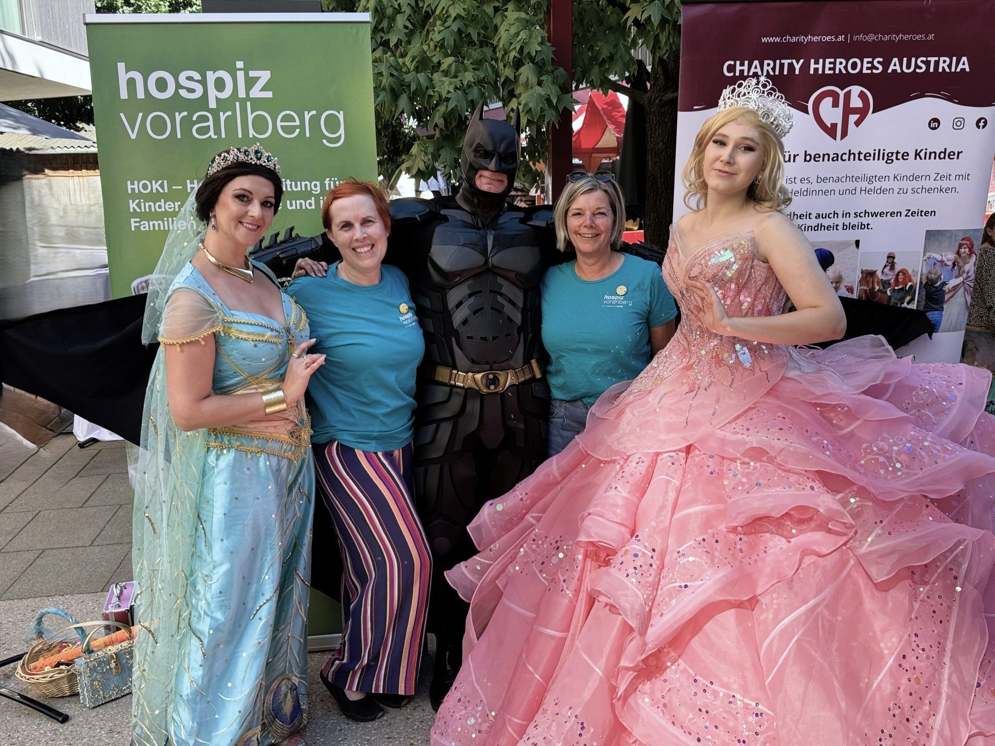Die Koordinatorinnen von HOKI Vorarlberg Sabine Mangeng und Silvia Mähr mit den Charity Heroes Prinzessin Jasmin, Batman und Glinda bei der Benefizveranstaltung am Garnmarkt.