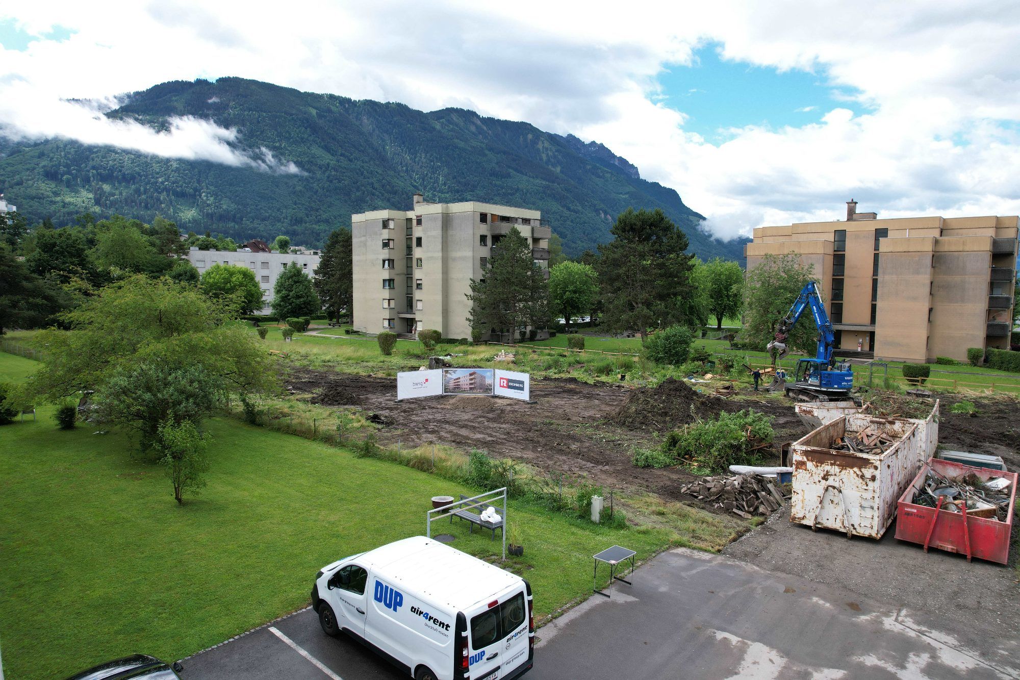 Blick über einen Teil des Grundstücks und der Grünfläche zwischen bestehenden und künftigen Gebäuden.