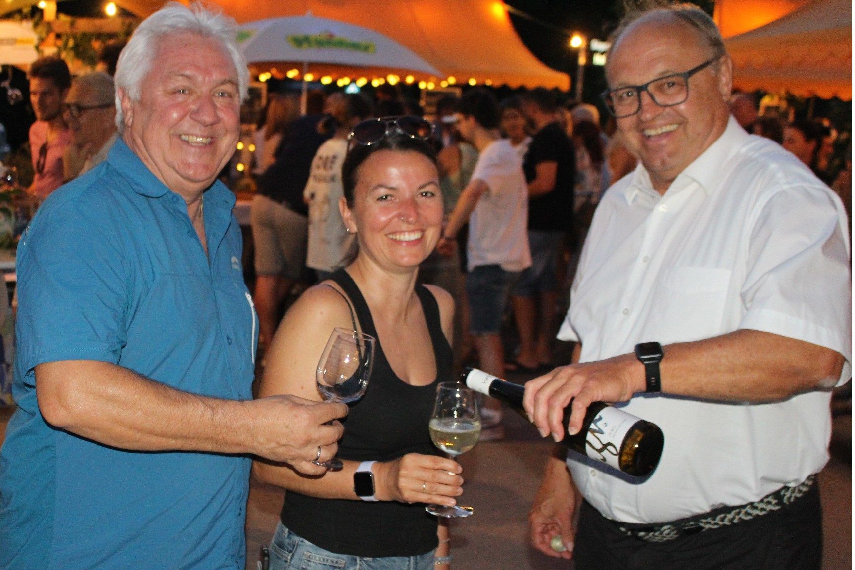 Bürgermeister Elmar Rhomberg schenkt Werner Hagen, und Miriam Lackner von der Markteting-Abteilung der Gemeinde ein, um auf das gelungene Winzer-Festival anzustoßen.   