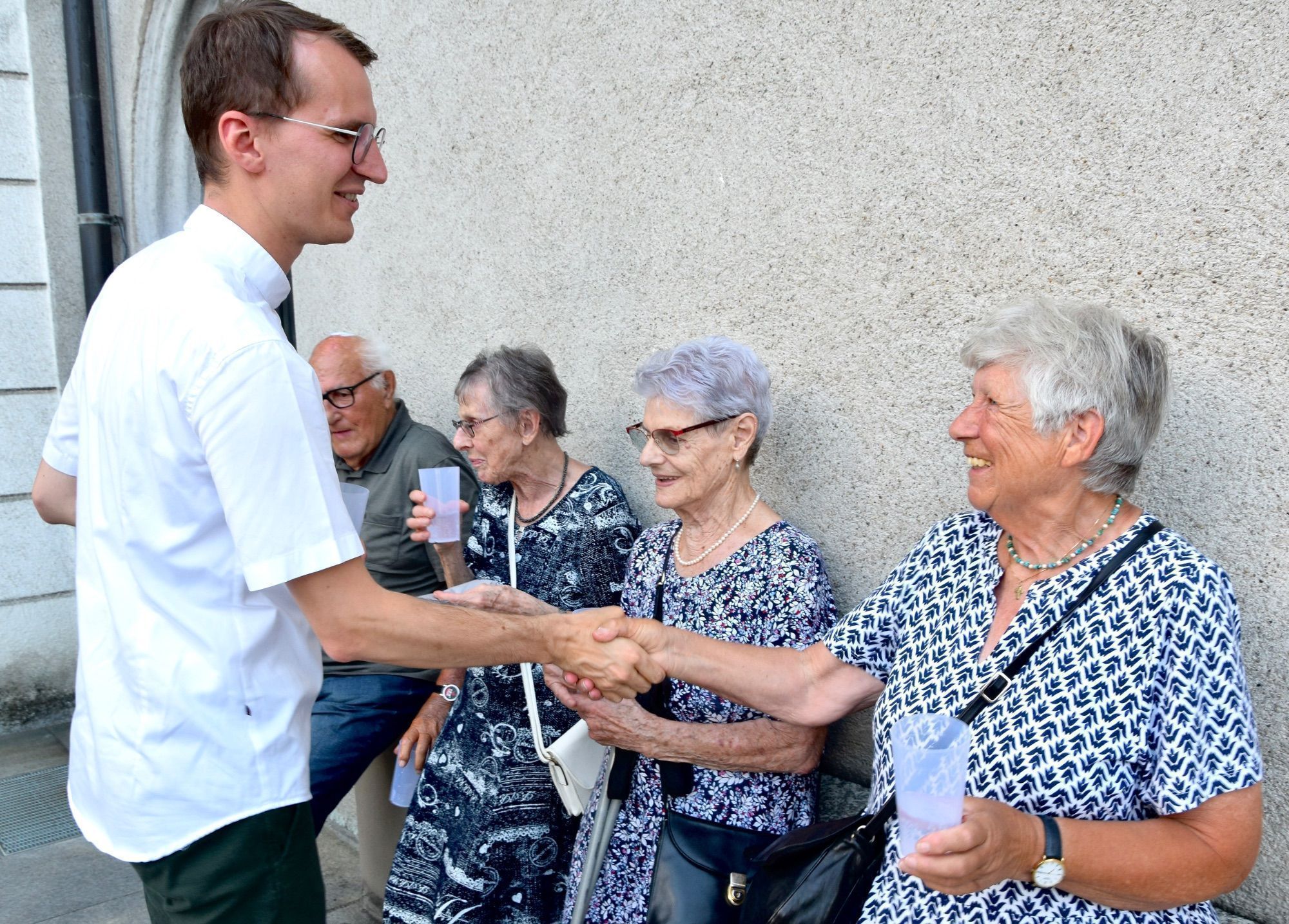 Kaplan Jakob Geier begrüßt treue Besucherinnen und Besucher der Patroziniumsfeier - rechts im Vordergrund: Herlinde Burtscher.