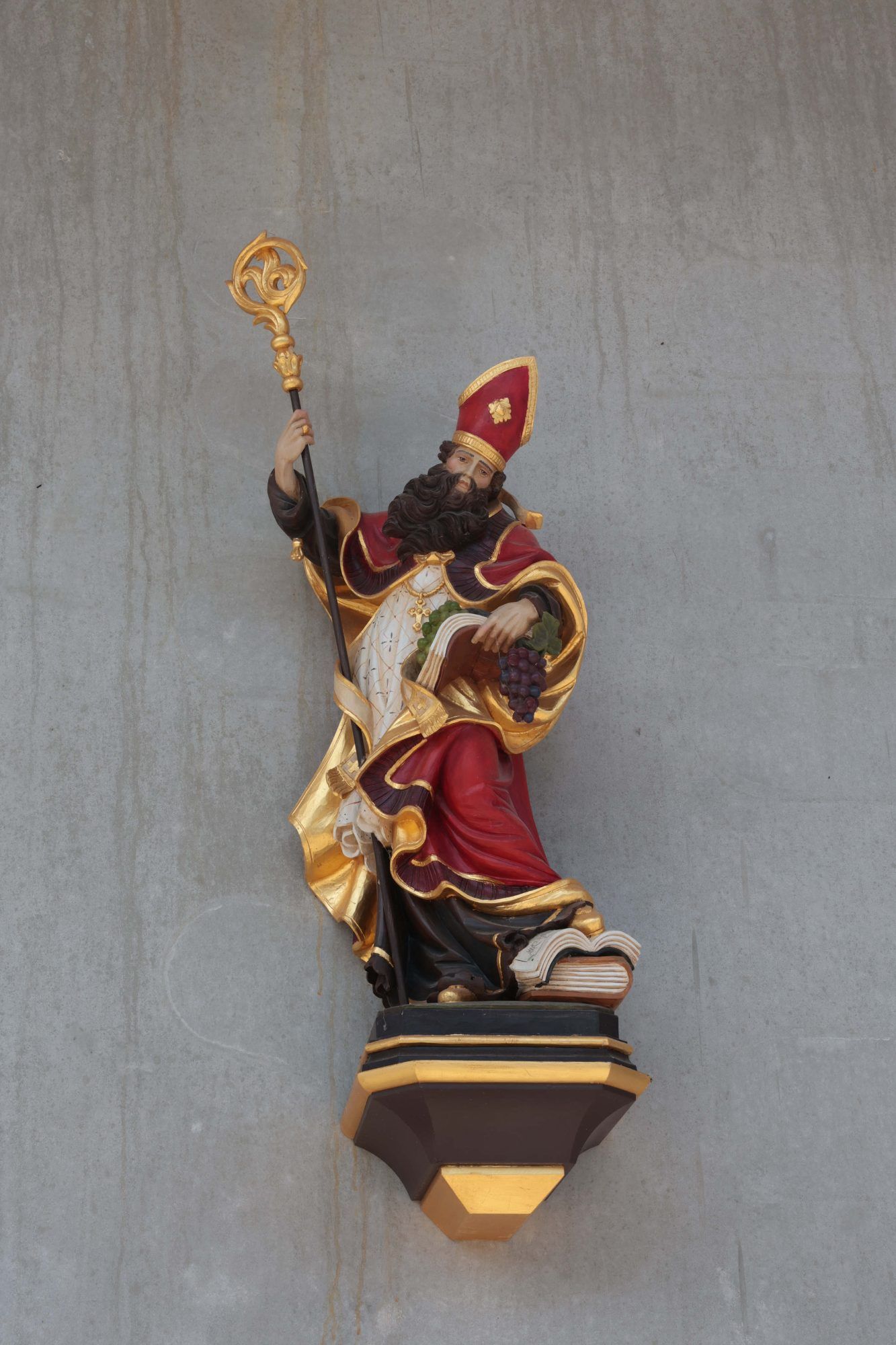 Auf der Vorderseite des voer vier Jahren in Betrieb genommenen Mehrzweckgebäudes: In Altötting geschnitzer Winzerpatron Urban.