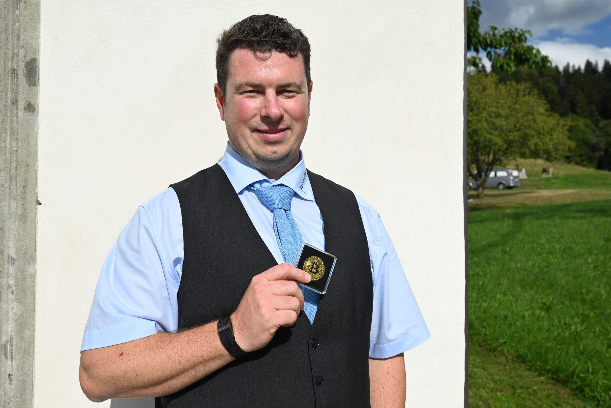 Bestatter Daniel Dalmonek von Bestattung Reumiller hält stolz eine symbolische Bitcoin Münze in der Hand. Ab sofort können bei ihnen Bestattungen auch mit der kryptischen Währung beglichen werden.