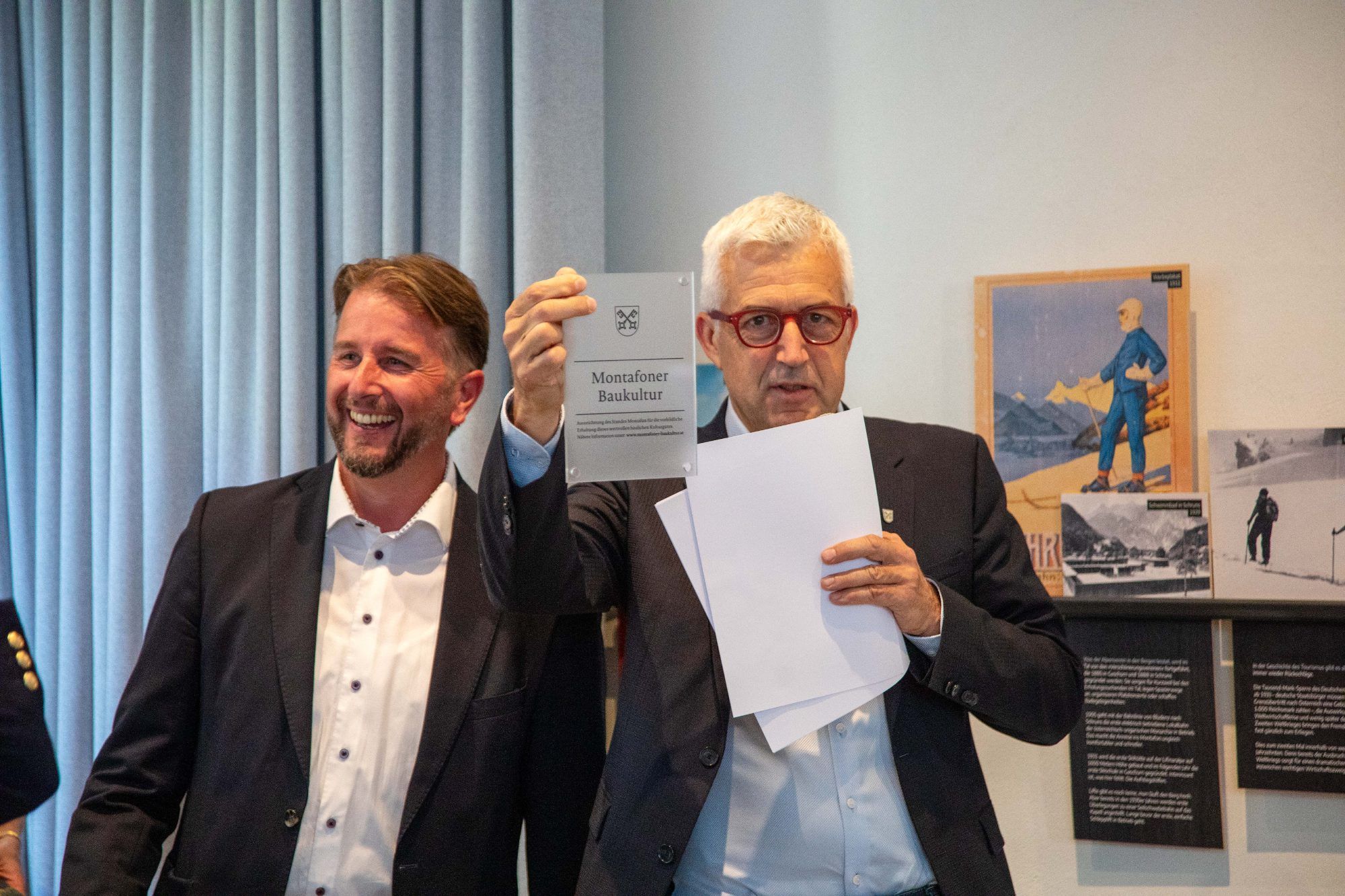 Standessekretär Bernhard Maier zeigt die Plakette, mit denen die ausgezeichneten Objekte gekennzeichnet werden.